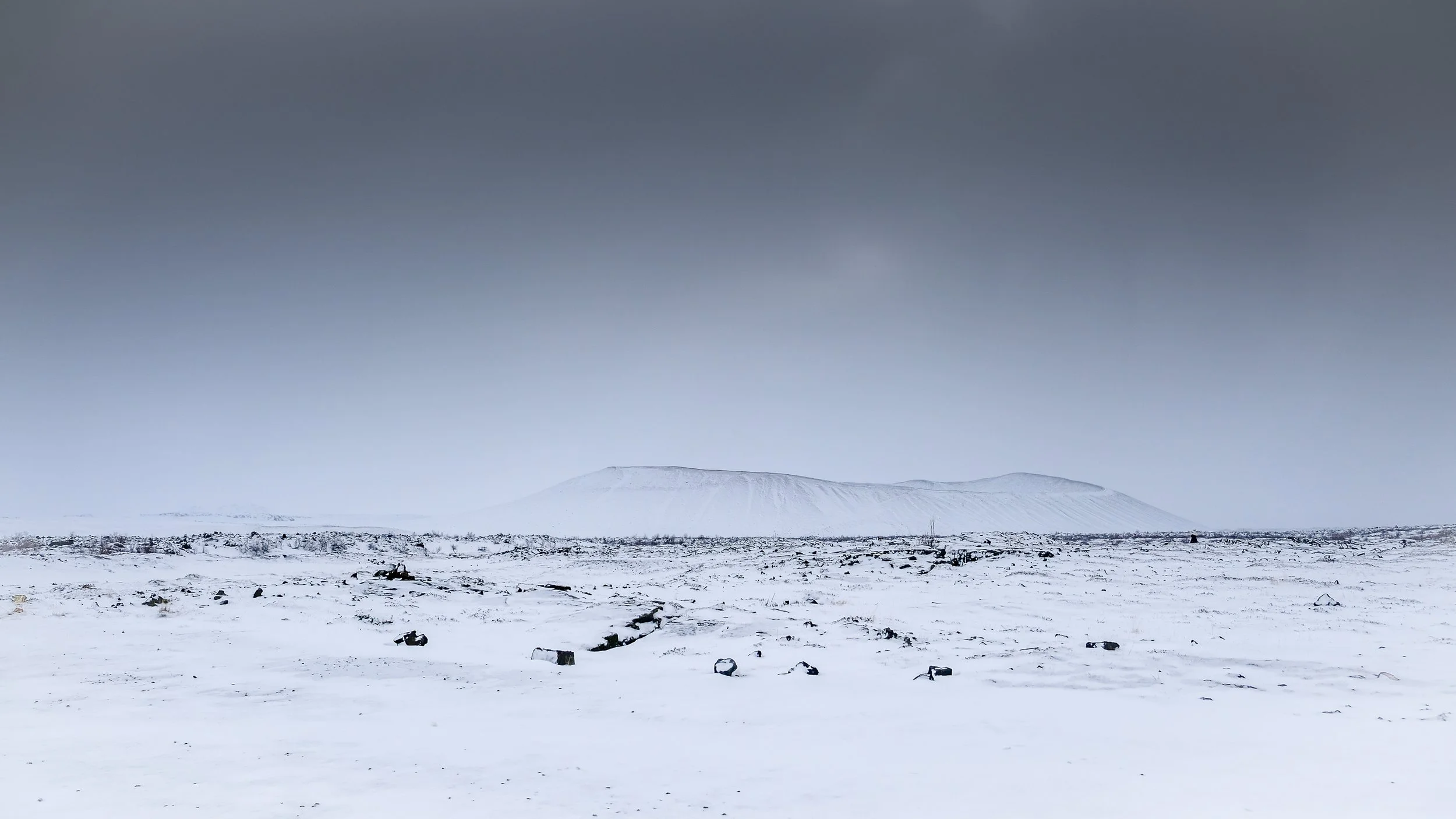 paysage de neige quasi-monochrome et minimaliste, volcan lointain dans la brume, esthétique "À minima".