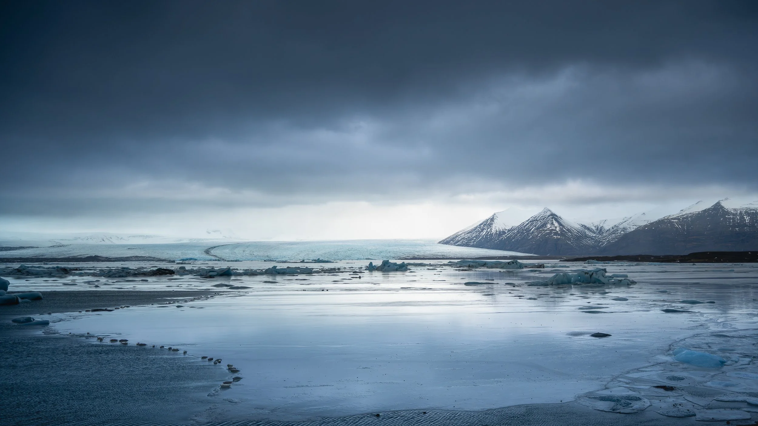 Phoqiues affalés sur des plaques de glace dsur la lagune de JOKULSARLOn, sous un ciel d'orage chargé, ambiance de solitude arctique.