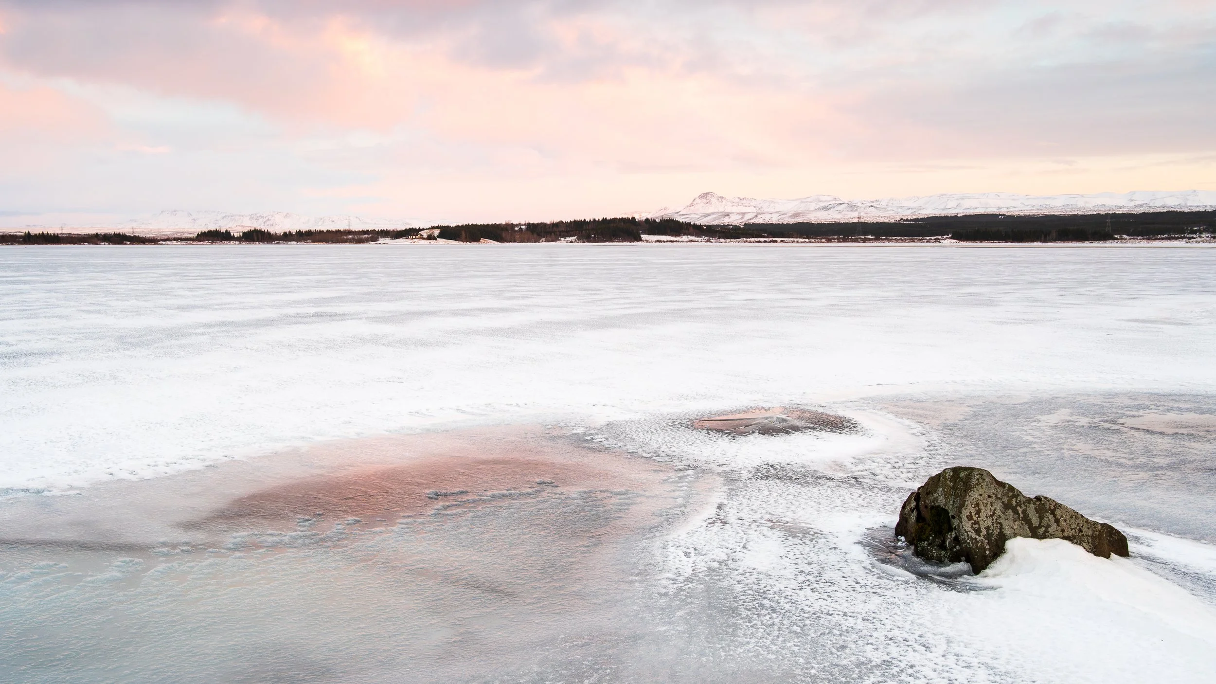 Plaine de glace sous une lumière rosée d'hiver, photographie épurée d'un lever de soleil sur un paysage figé en Islande.