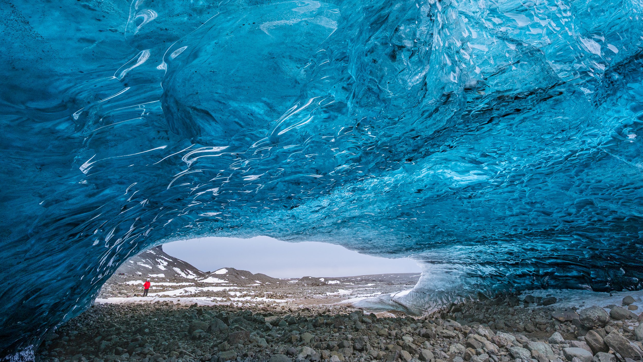 Vue immersive depuis l'intérieur d'une grotte de glace bleue, transparence et lumière naturelle au cœur du glacier.
