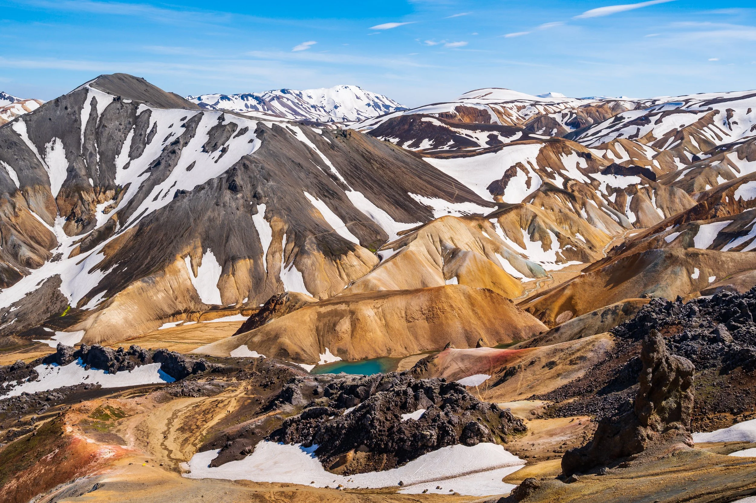 Chaîne de montagnes escarpées du Landmannalaugar avec contrastes de neige et de roches minérales, photographie de paysage.