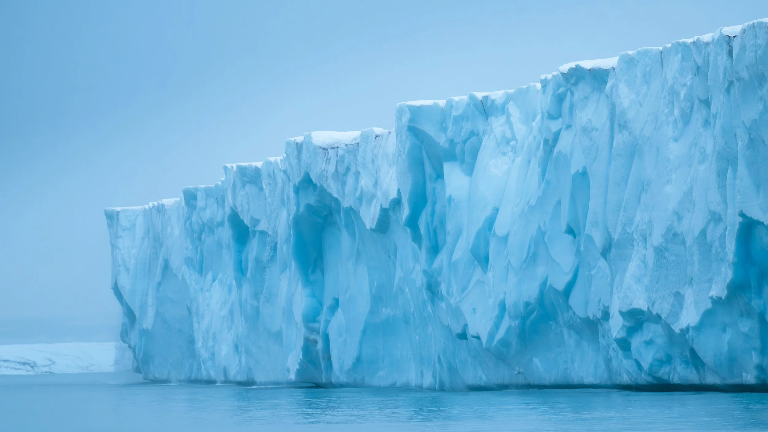 Falaises de glace au Spitsberg.  	 glace)	Détail imposant d'une paroi de glacier aux teintes bleutées, texture de la glace millénaire et puissance des éléments.