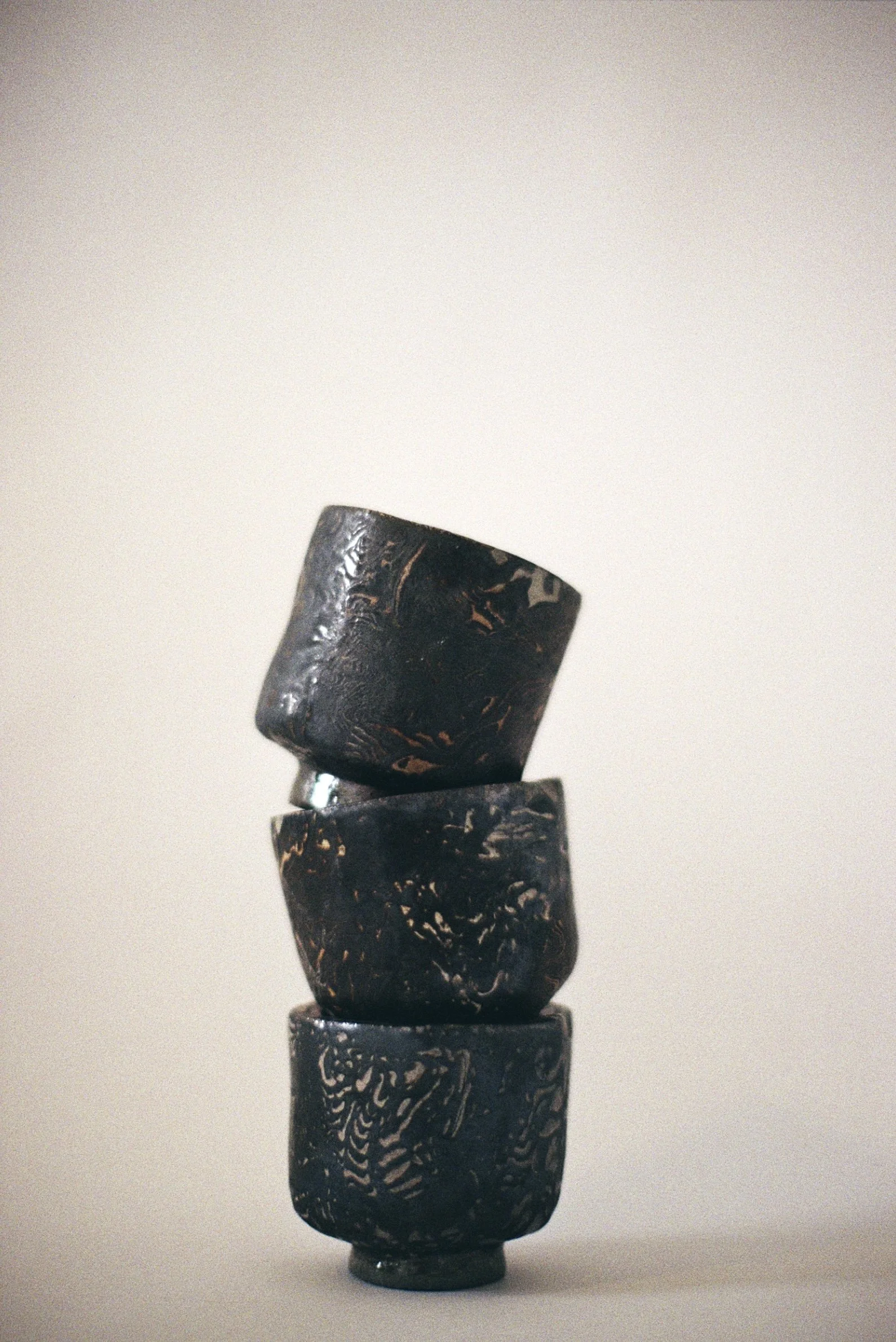 Stacked black ceramic bowls with a textured surface, set against a plain light background.
