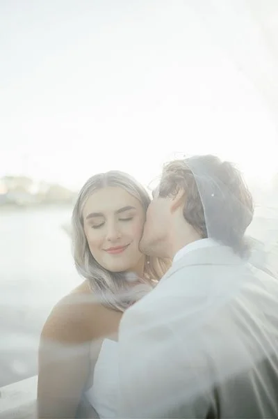 bride groom under wedding veil with soft sunset