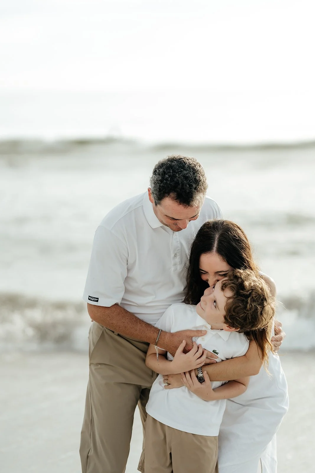 mom and dad with their son on jacksonville beach shot by hailee Cataldi photo