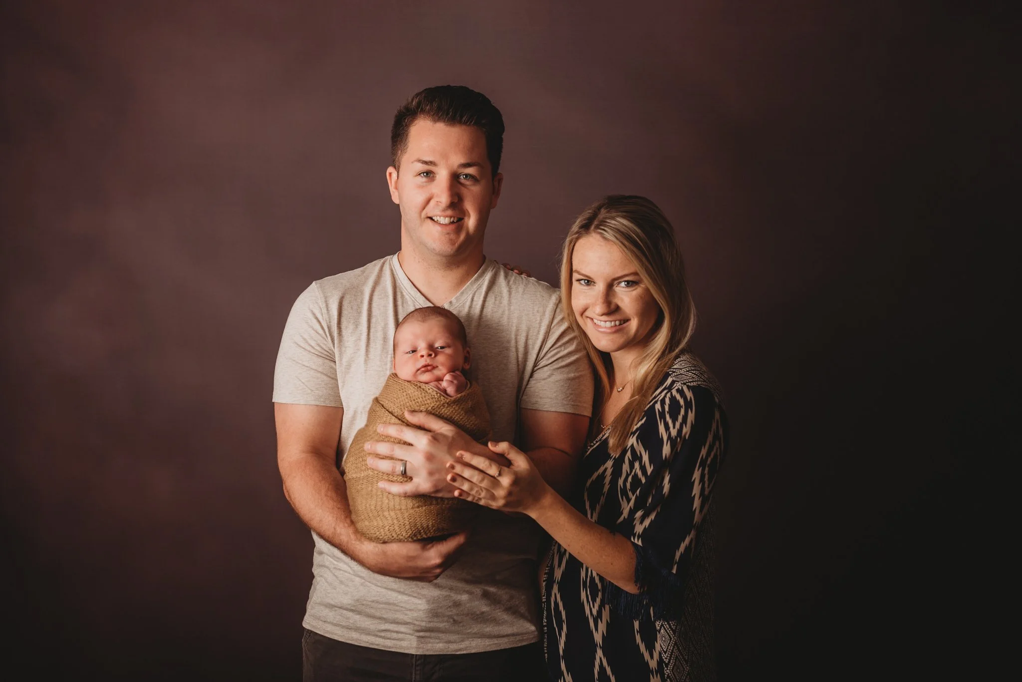 Family portrait with parents holding newborn baby.