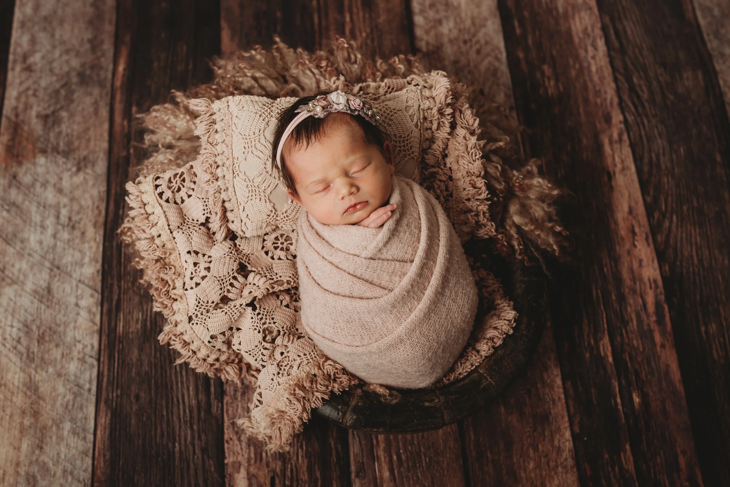 Sleeping newborn wrapped in blanket, wooden background