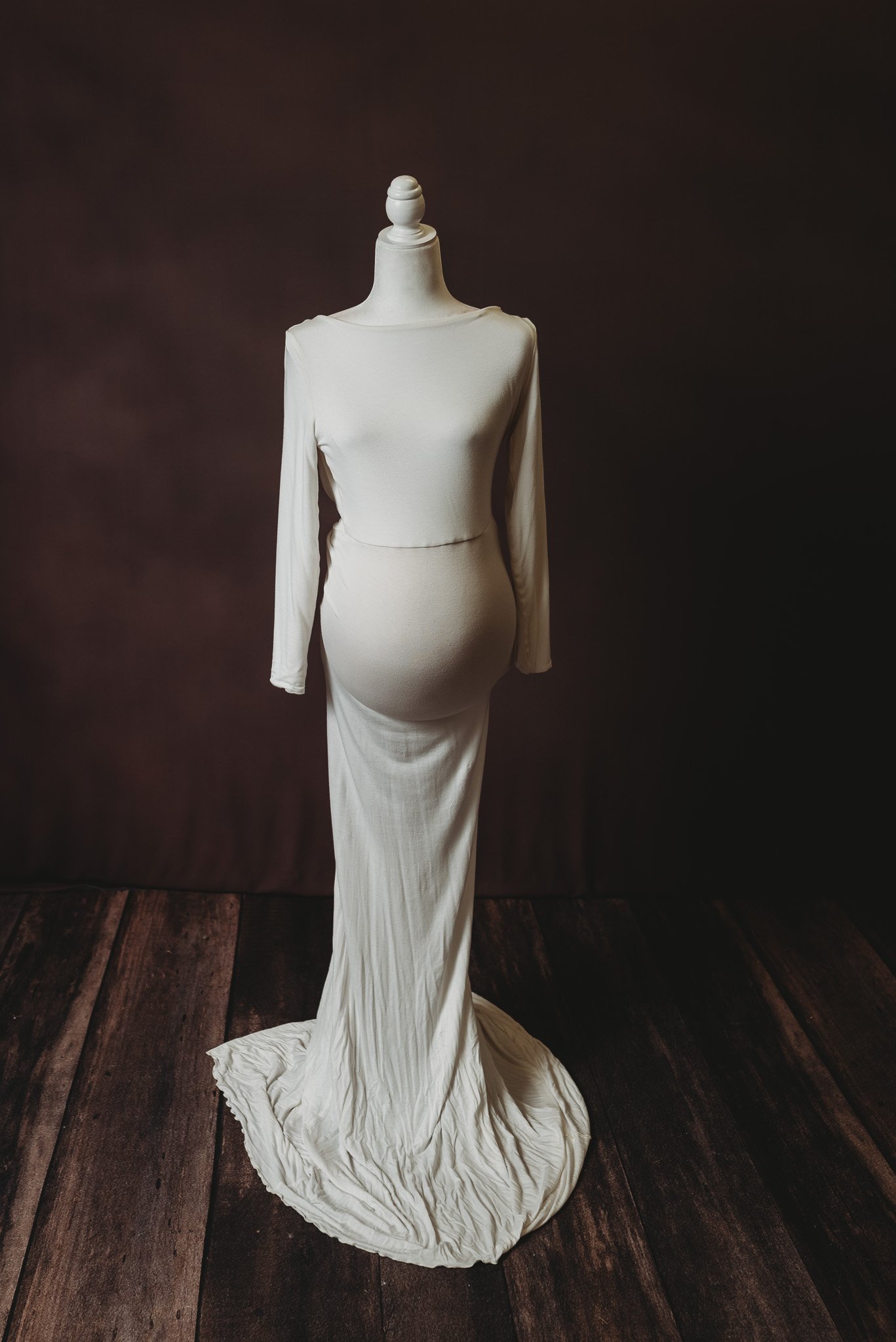 White maternity gown on mannequin against dark background