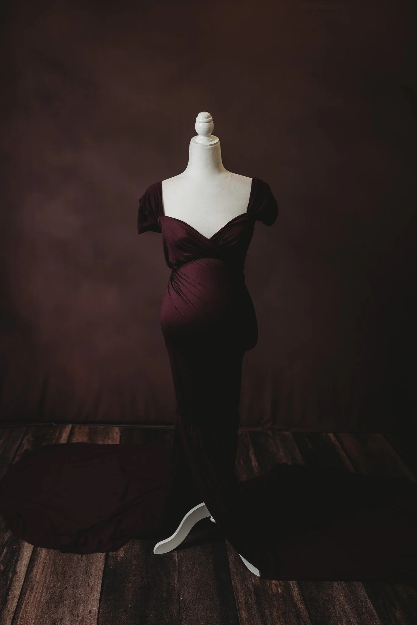 Mannequin wearing dark red maternity dress against dark background