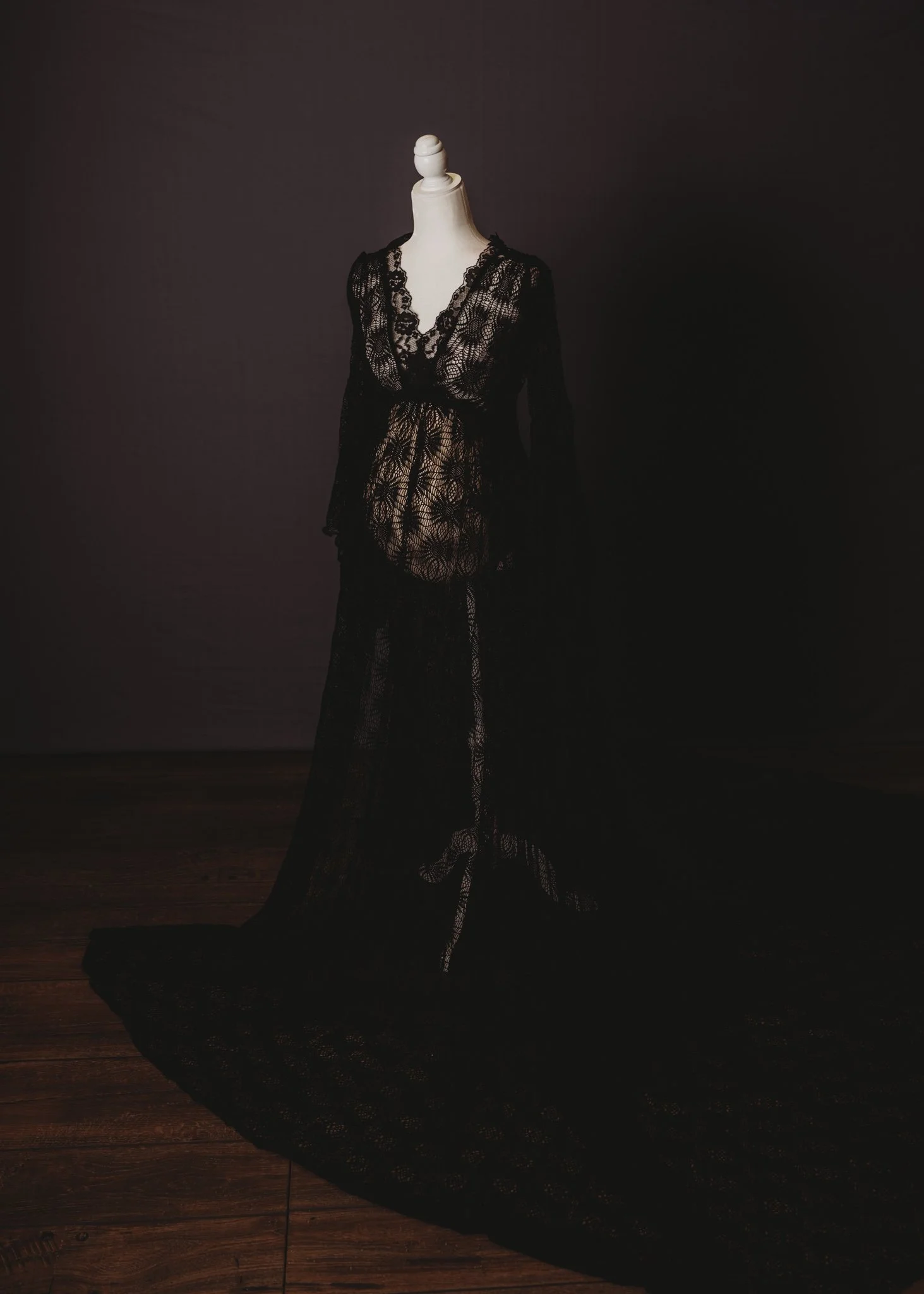 Mannequin wearing translucent black lace gown on dark background