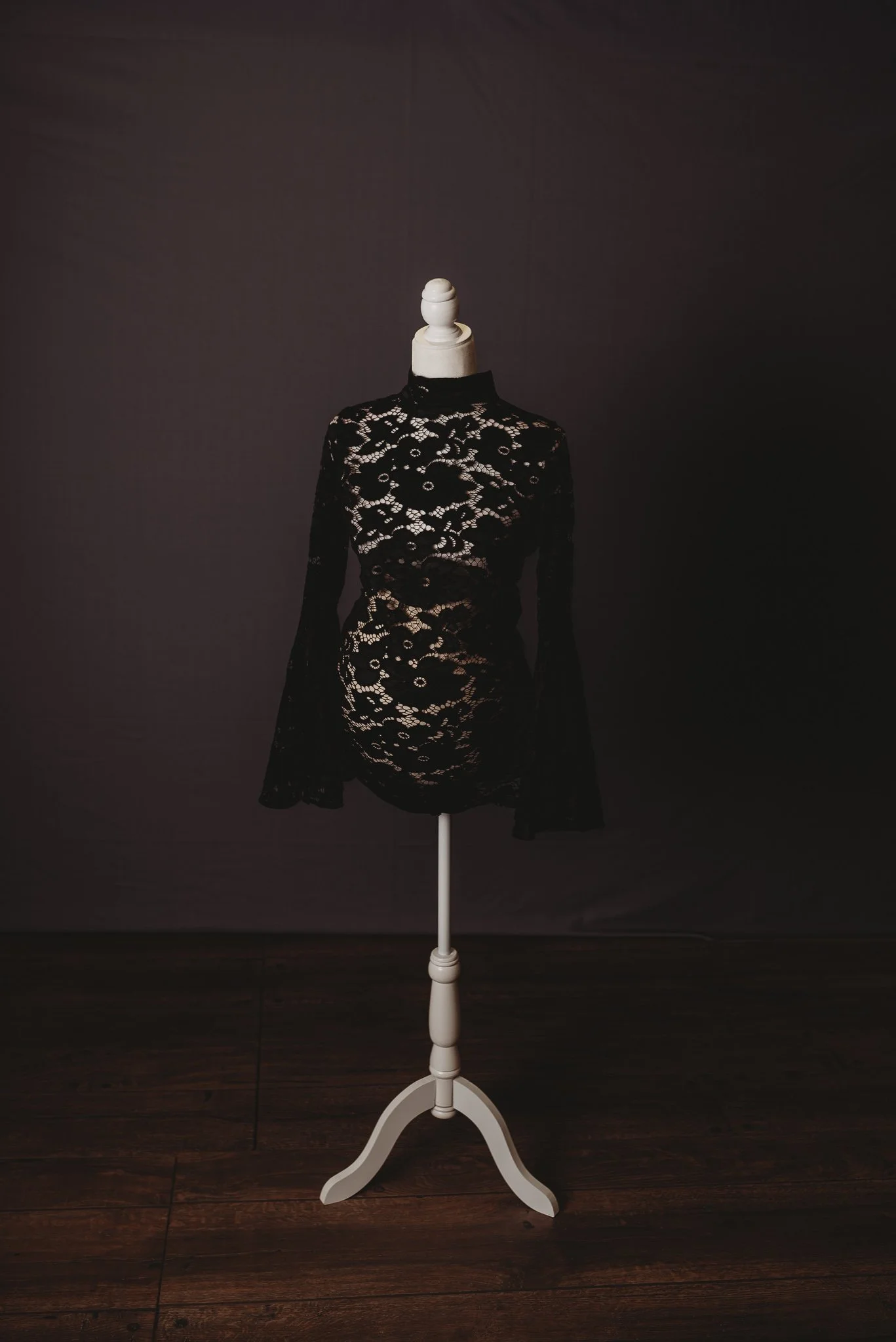 Lace maternity dress on mannequin against dark background