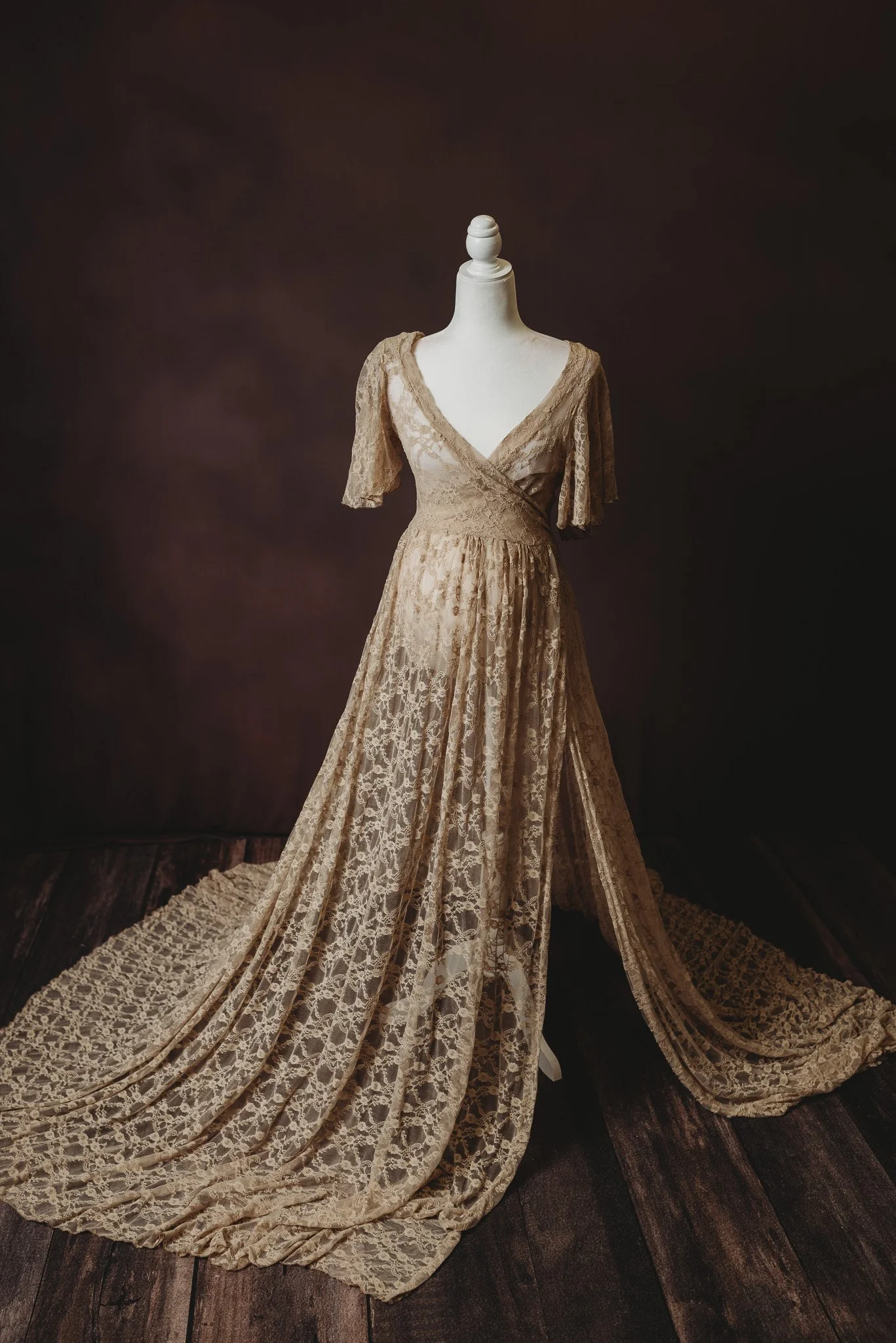 Elegant vintage lace dress on mannequin with dark background.