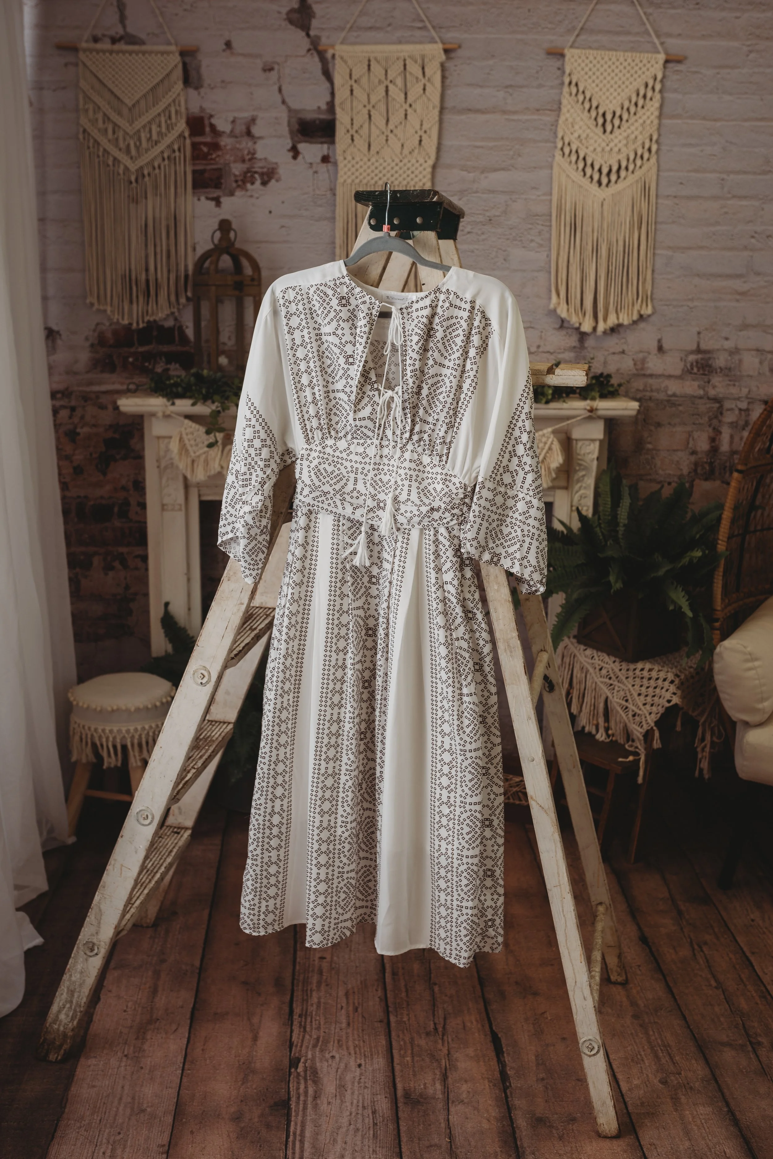 Bohemian-style dress on wooden ladder with macrame wall decor and rustic interior.