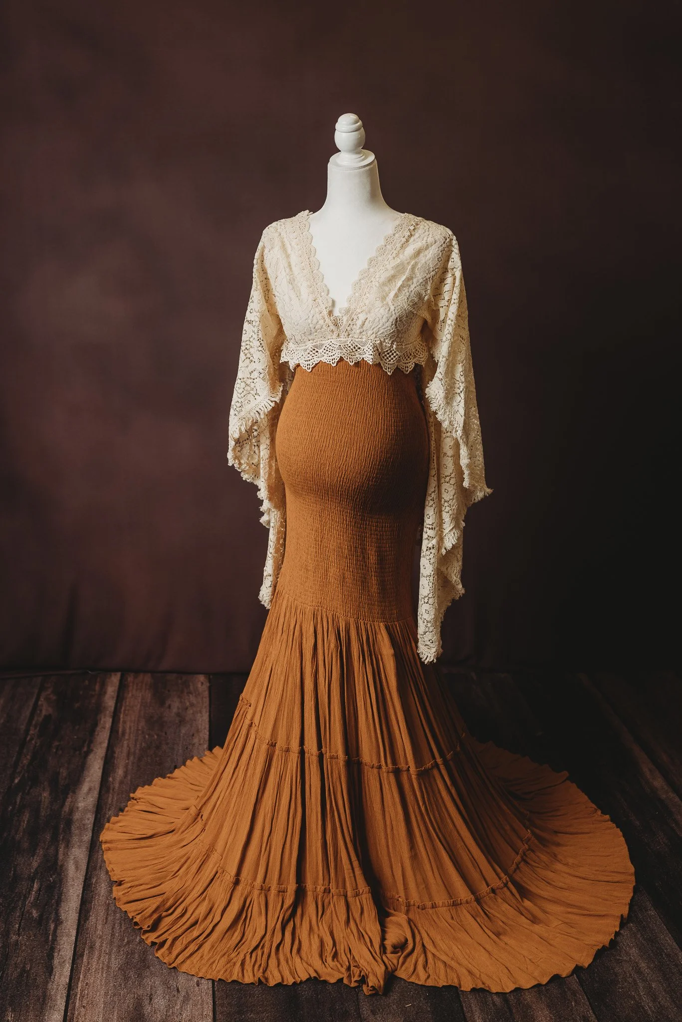 Vintage brown maternity dress with lace detailing on mannequin against dark background