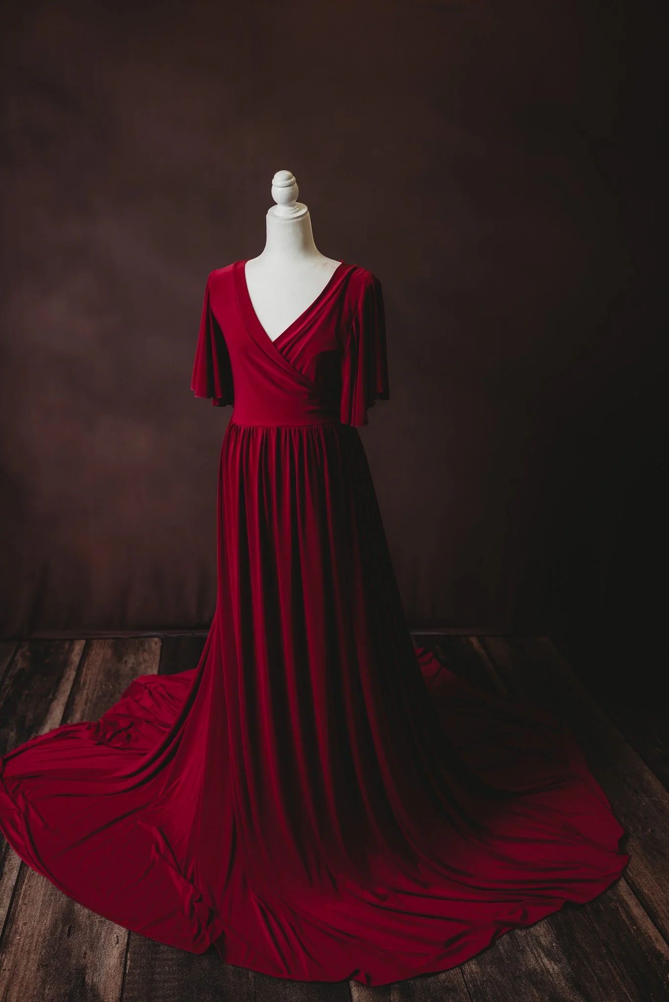 Elegant red gown displayed on a mannequin against a dark background.