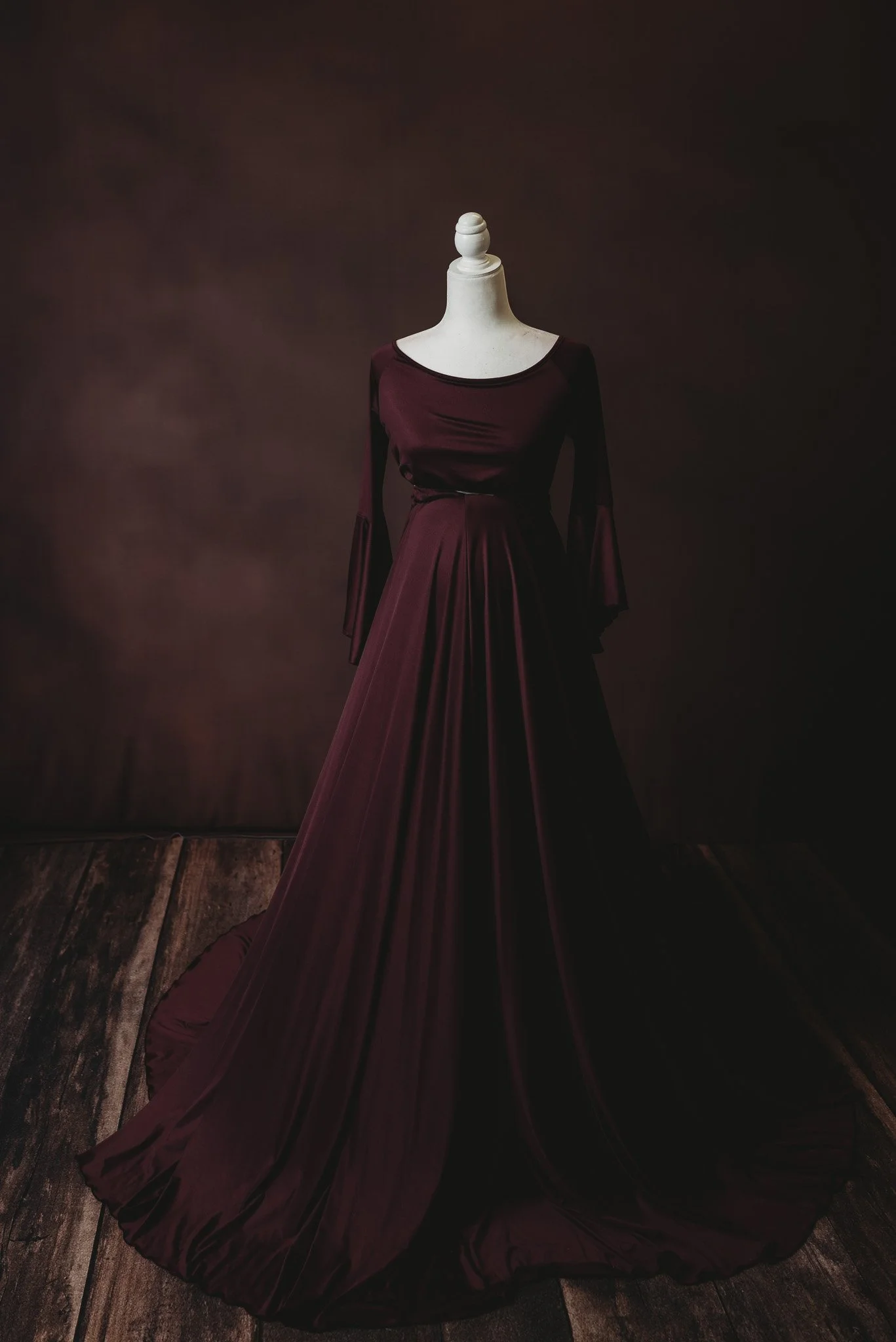 Elegant maroon gown on a mannequin against a dark background.