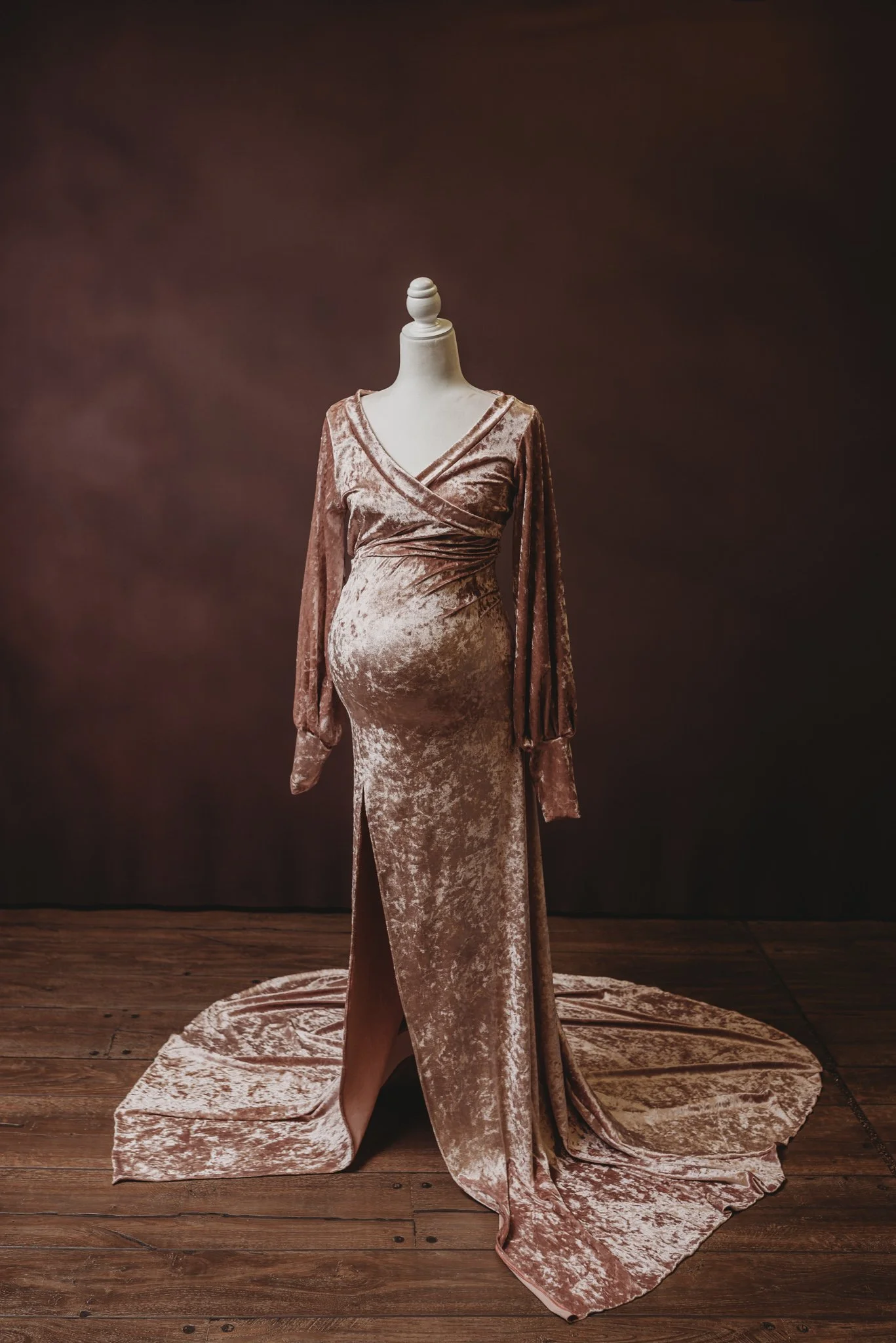 mannequin wearing long velvet maternity dress on wooden floor