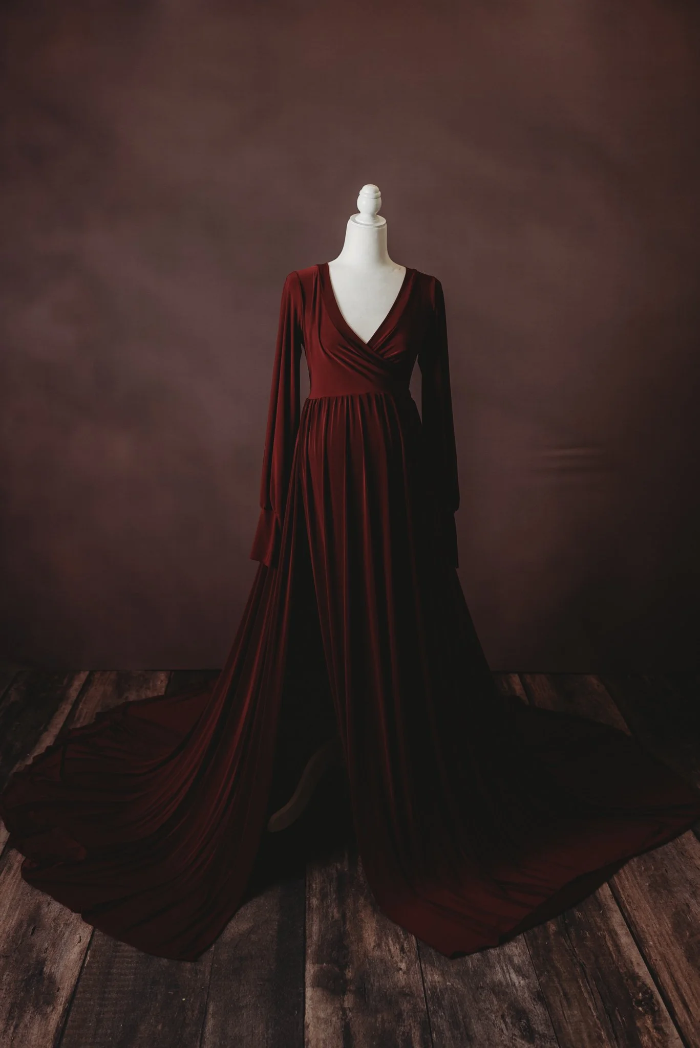 Elegant burgundy gown on mannequin in dark room