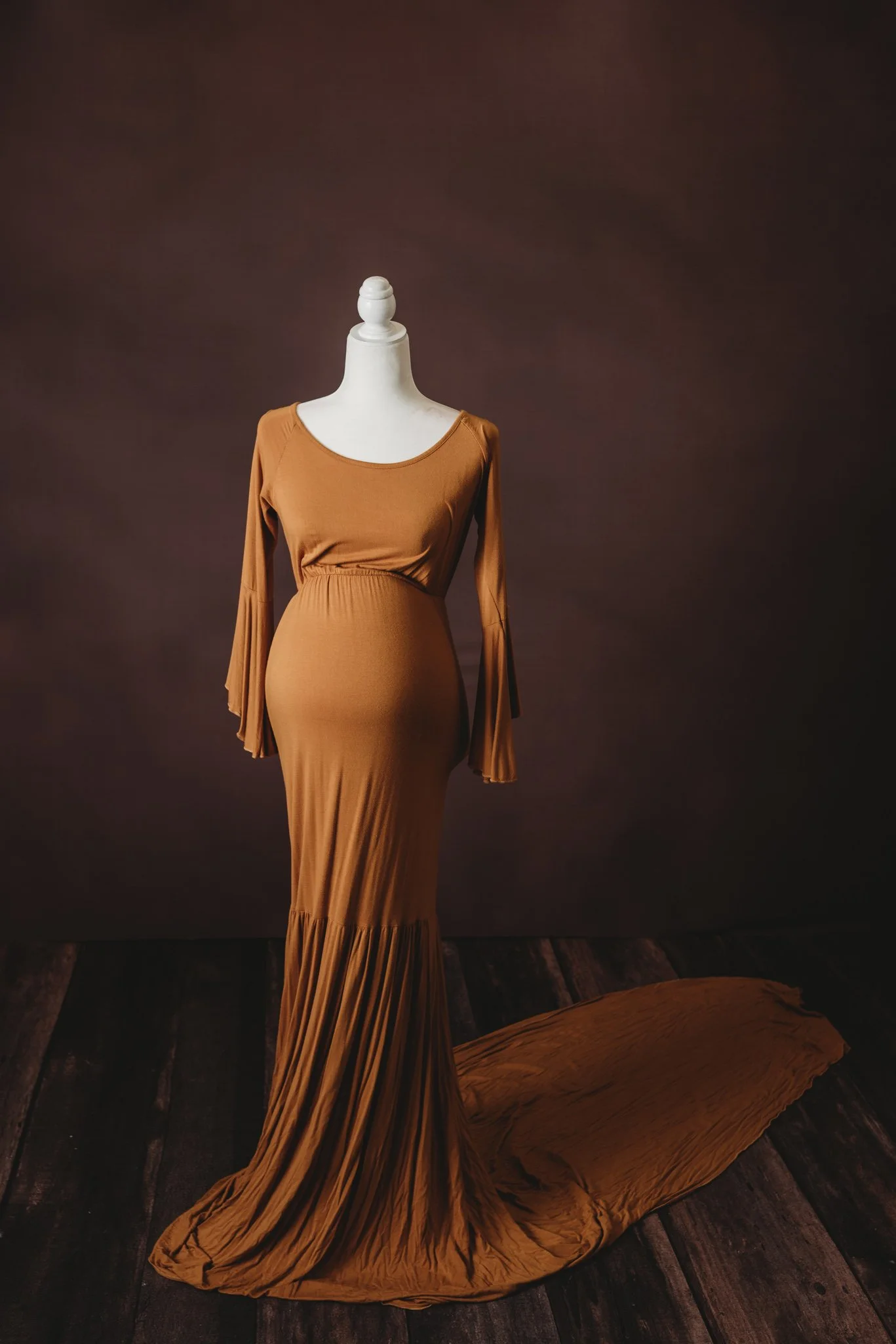 Long brown maternity dress on a mannequin with dark background
