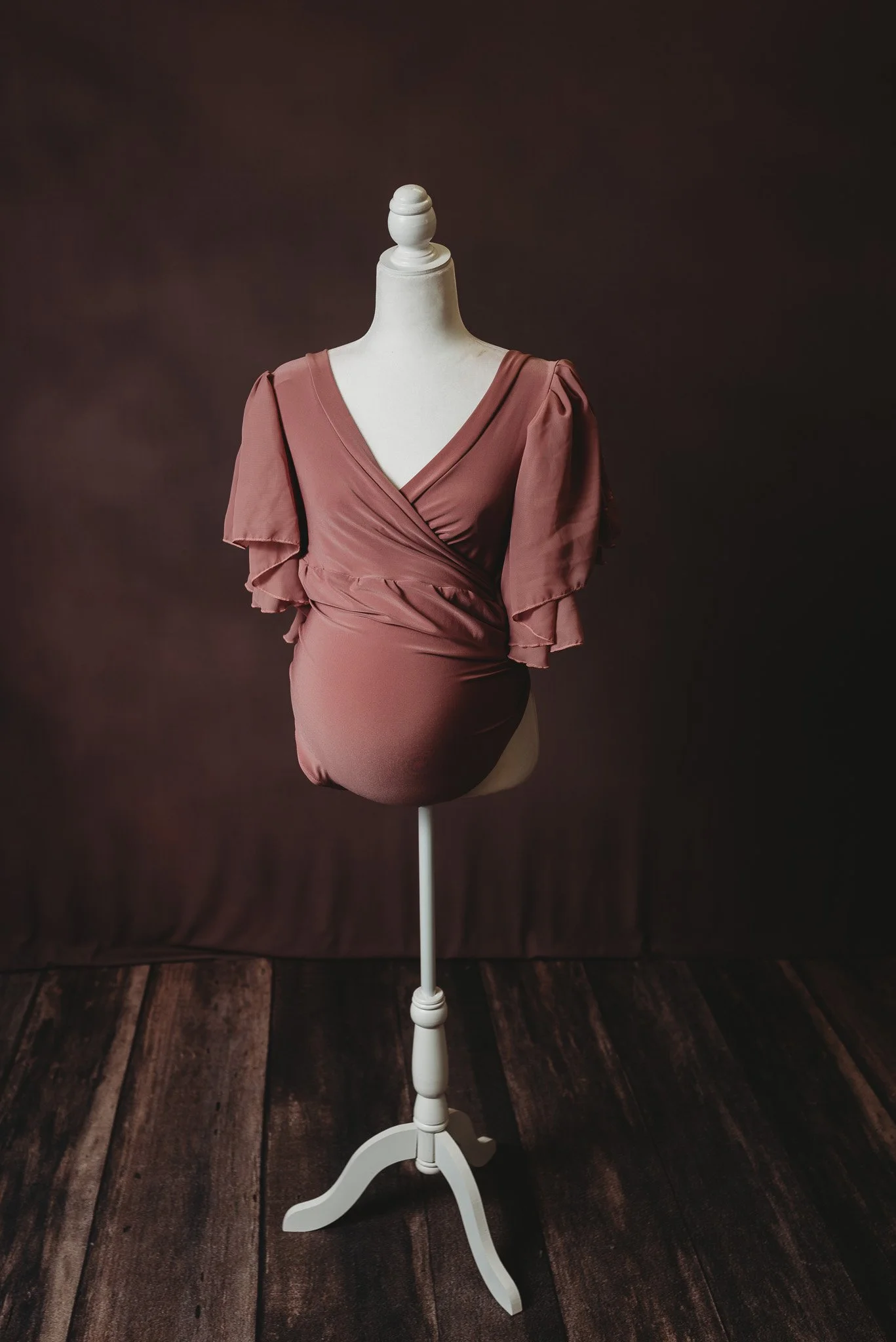 Maternity dress displayed on a mannequin with a brown background.