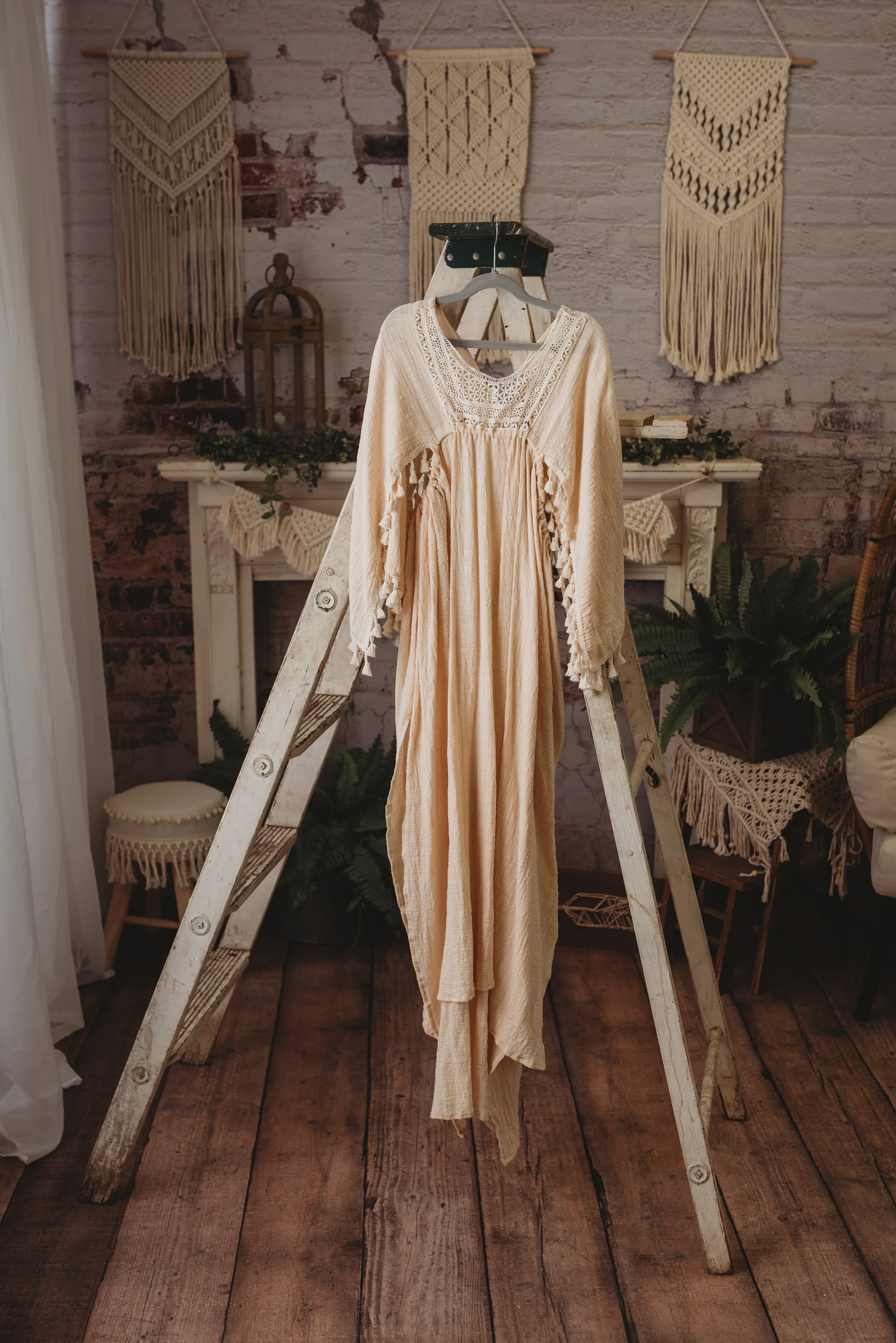 Bohemian style dress on a wooden ladder with macrame wall hangings and rustic decor.