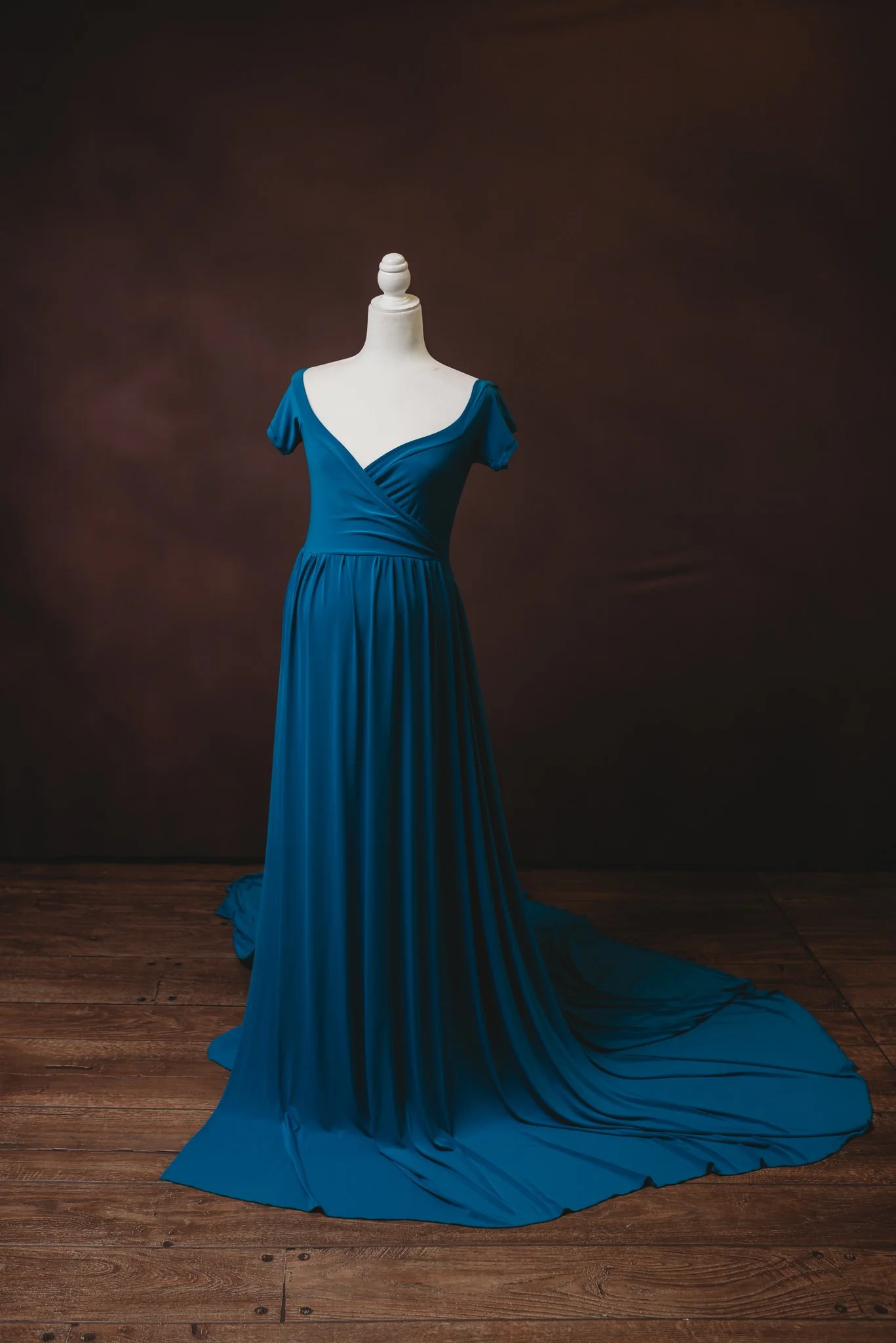 Elegant blue evening gown on mannequin with V-neck, short sleeves, and flowing skirt.