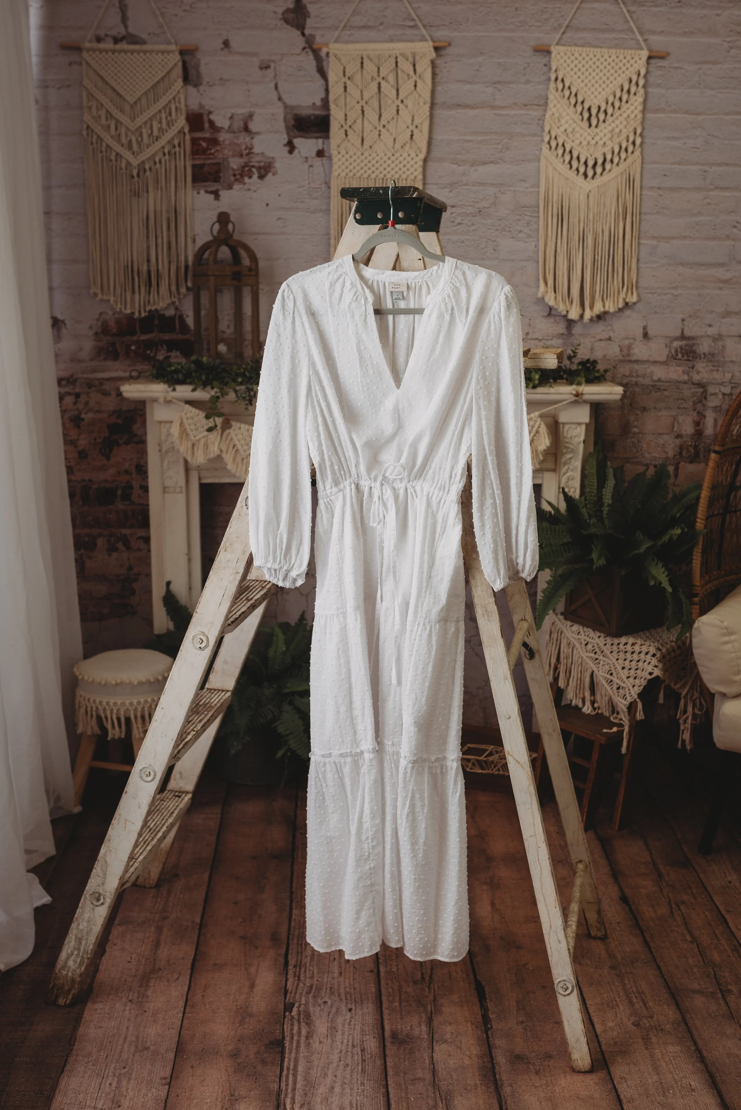 White dress on wooden ladder with bohemian decor background.