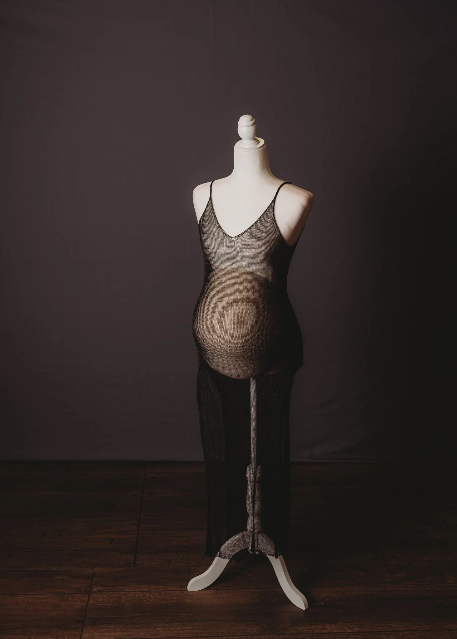 Mannequin wearing a sheer black maternity dress.