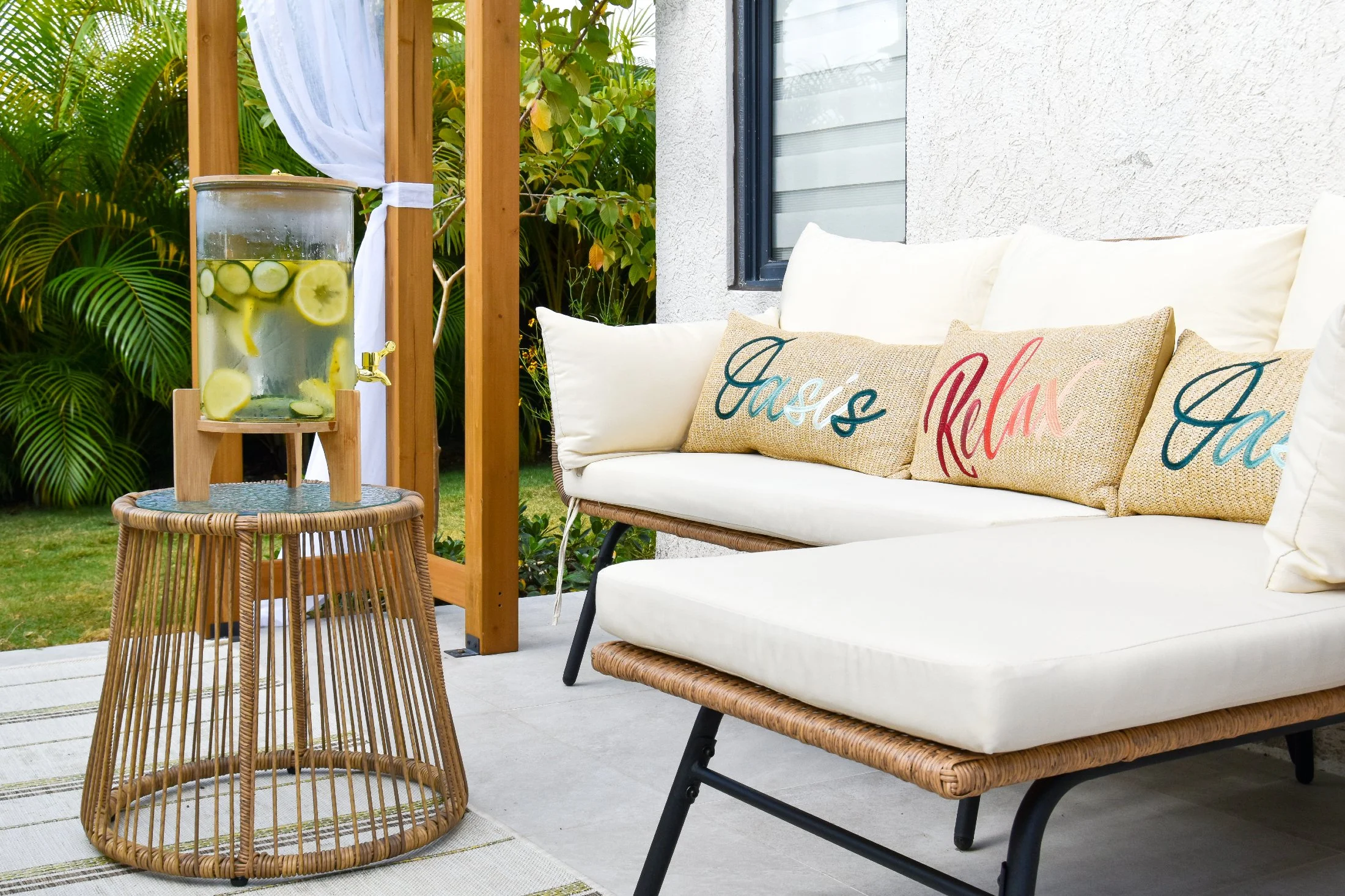 Comfortable outdoor lounge sofa with tropical greenery and refreshing infused water at Luxe Oasis private vacation villa in Ocho Rios, Jamaica.
