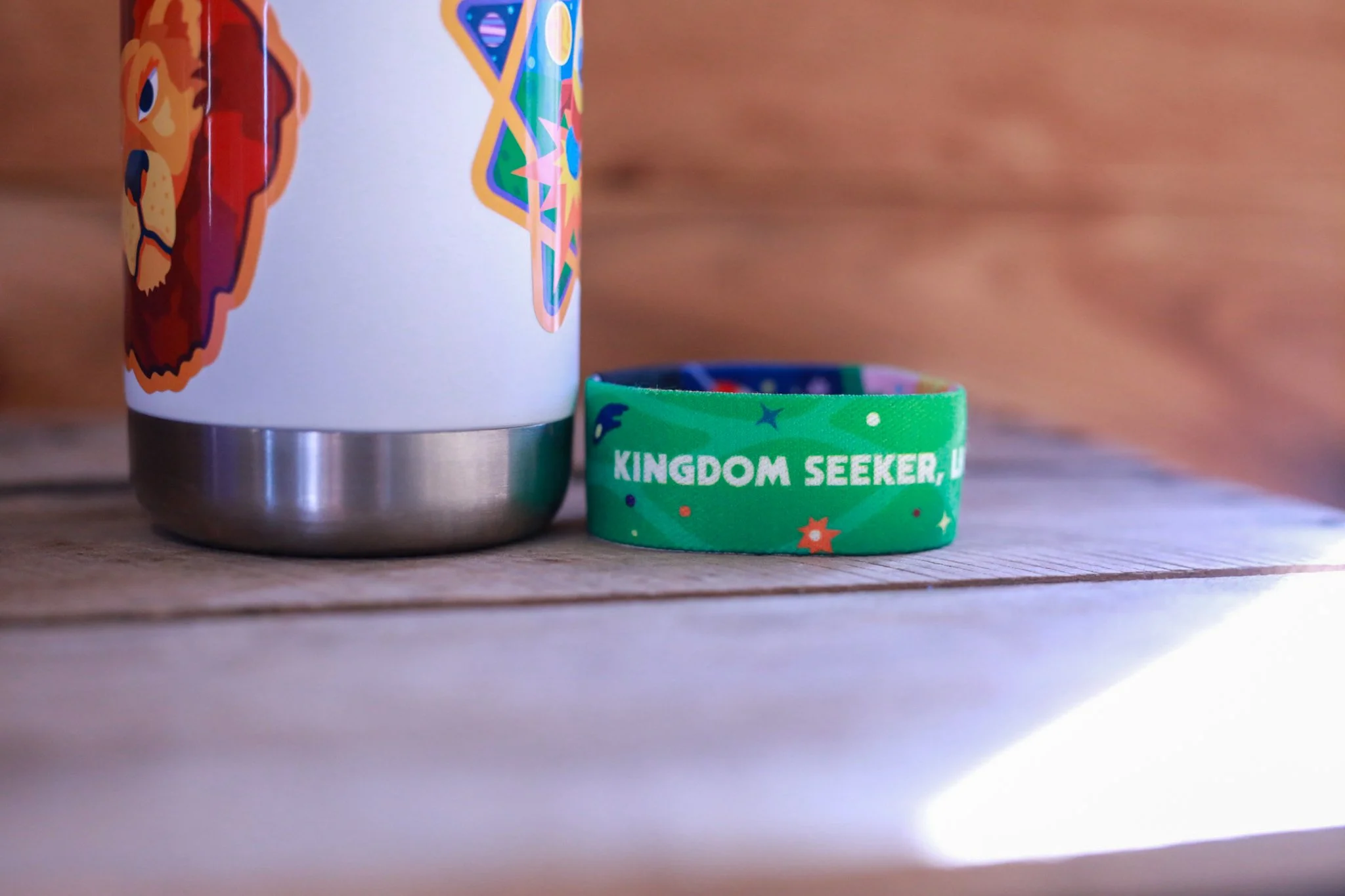 Two people wearing blue shirts and black pants, showing their wrists adorned with matching live out bracelets. One person has a red bandana tied around their left thigh.