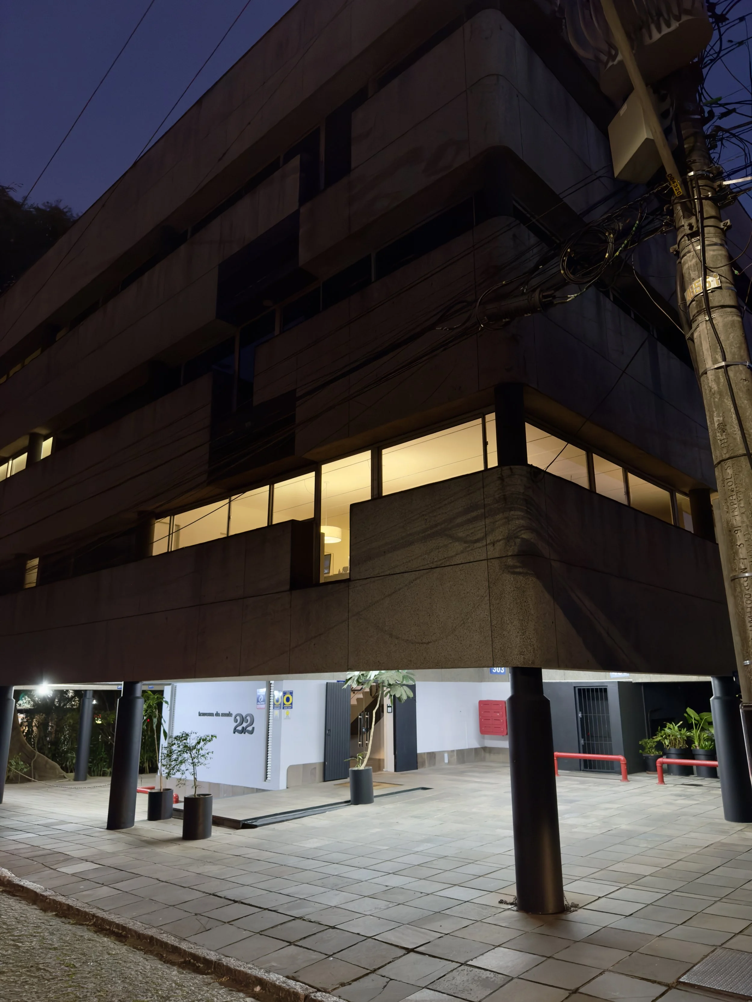 Foto de predio ao anoitecer, luzes acesas em um dos andares