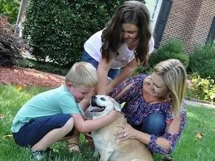 lady and kids with a dog in the grass