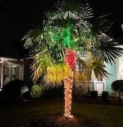 Columns on a house wrapped with white lights and red ribbon