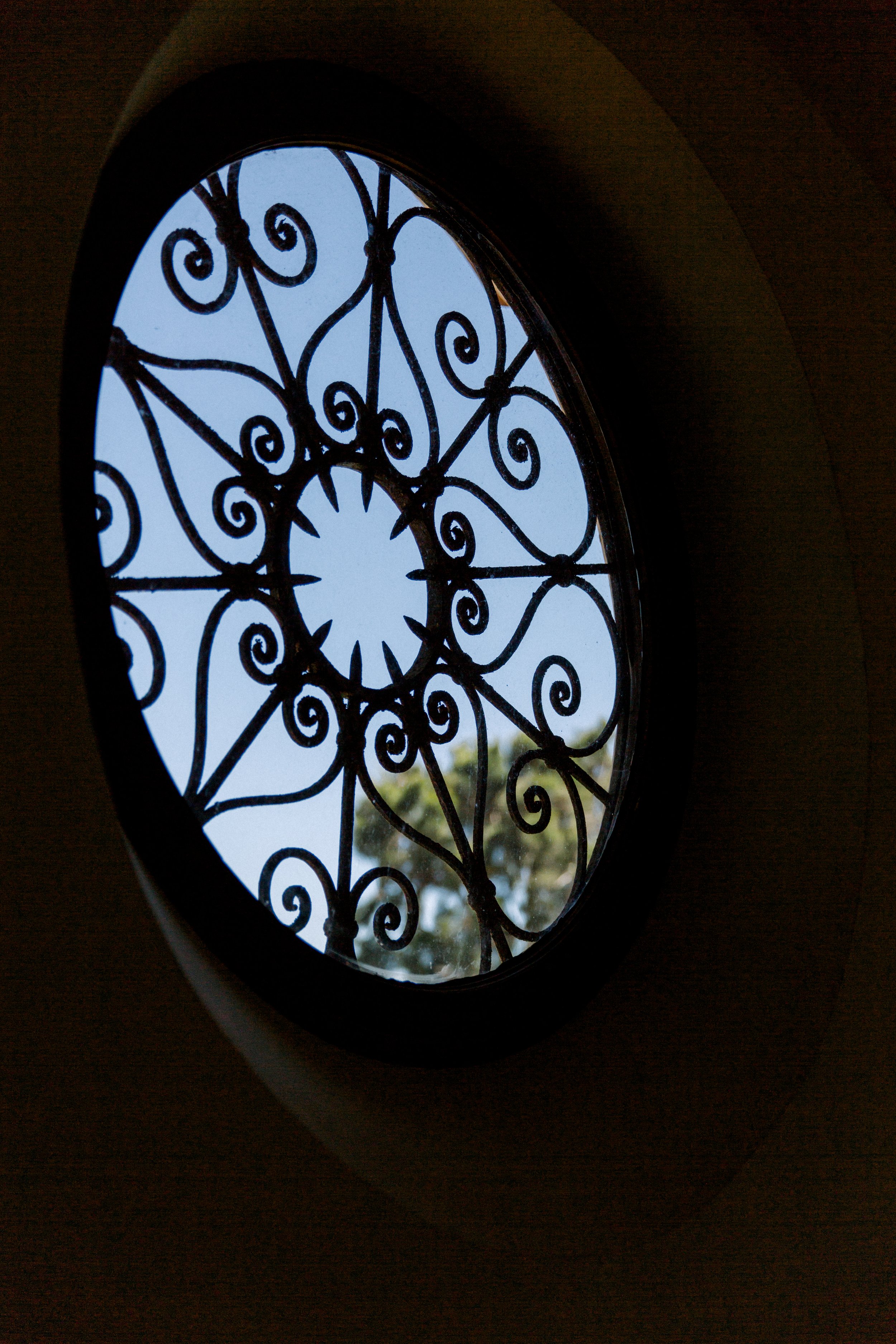 Oval window with decorative wrought iron grille and blue sky background