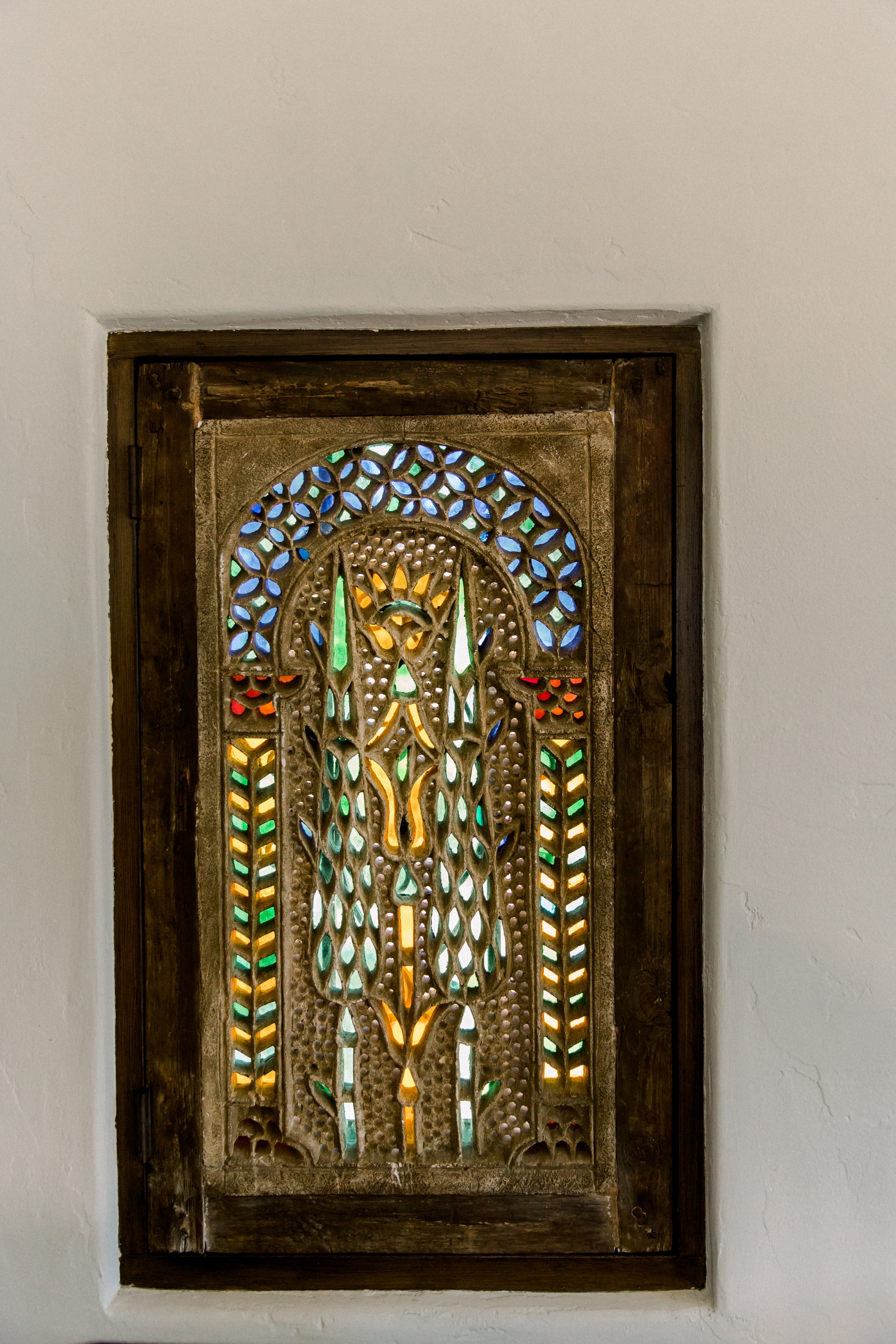 Decorative stained glass window with colorful geometric patterns set in a wooden frame.