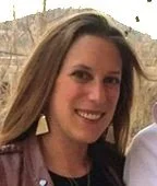 Smiling person outdoors with hills in background