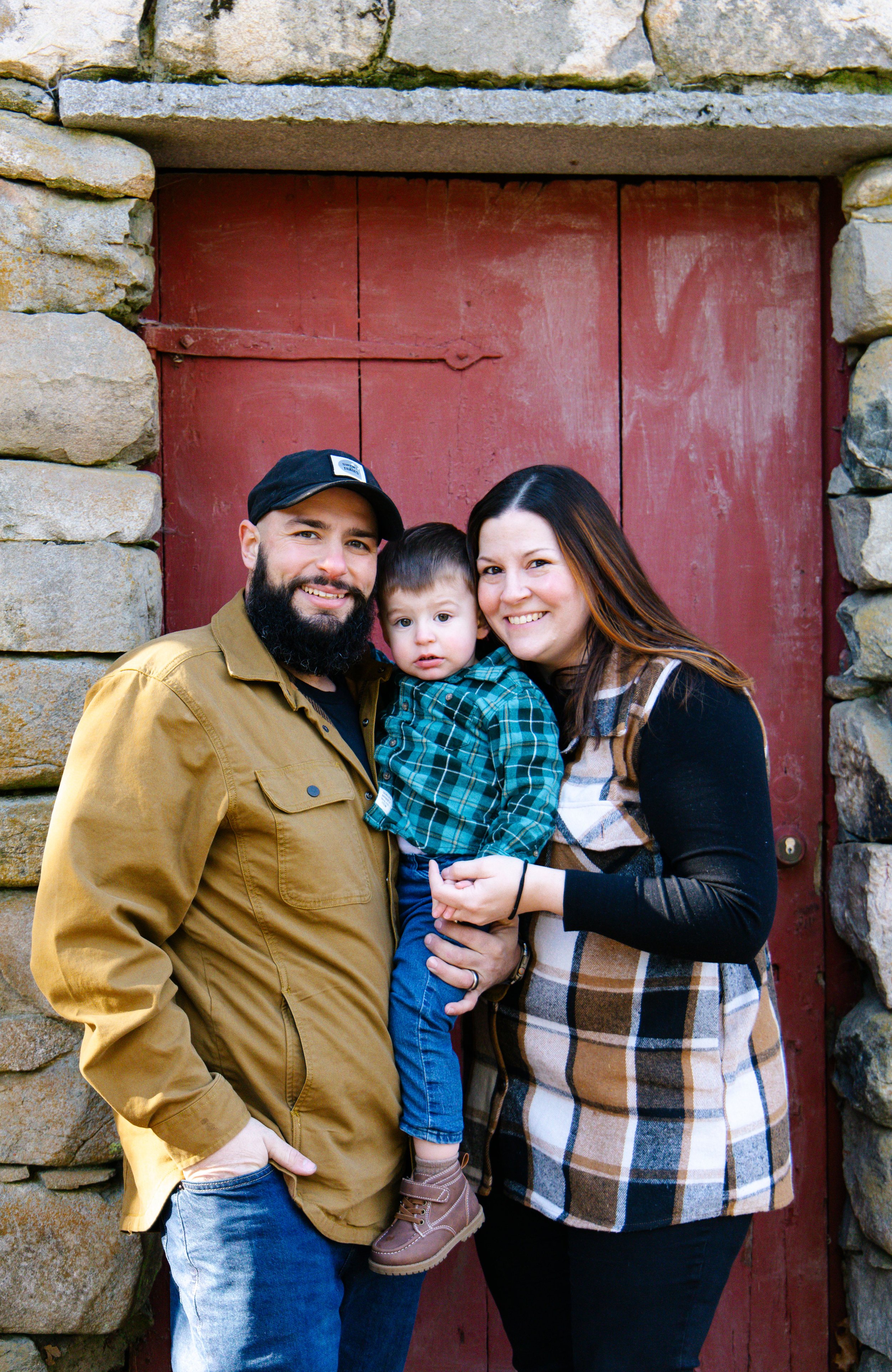 A family of three in front of a red door