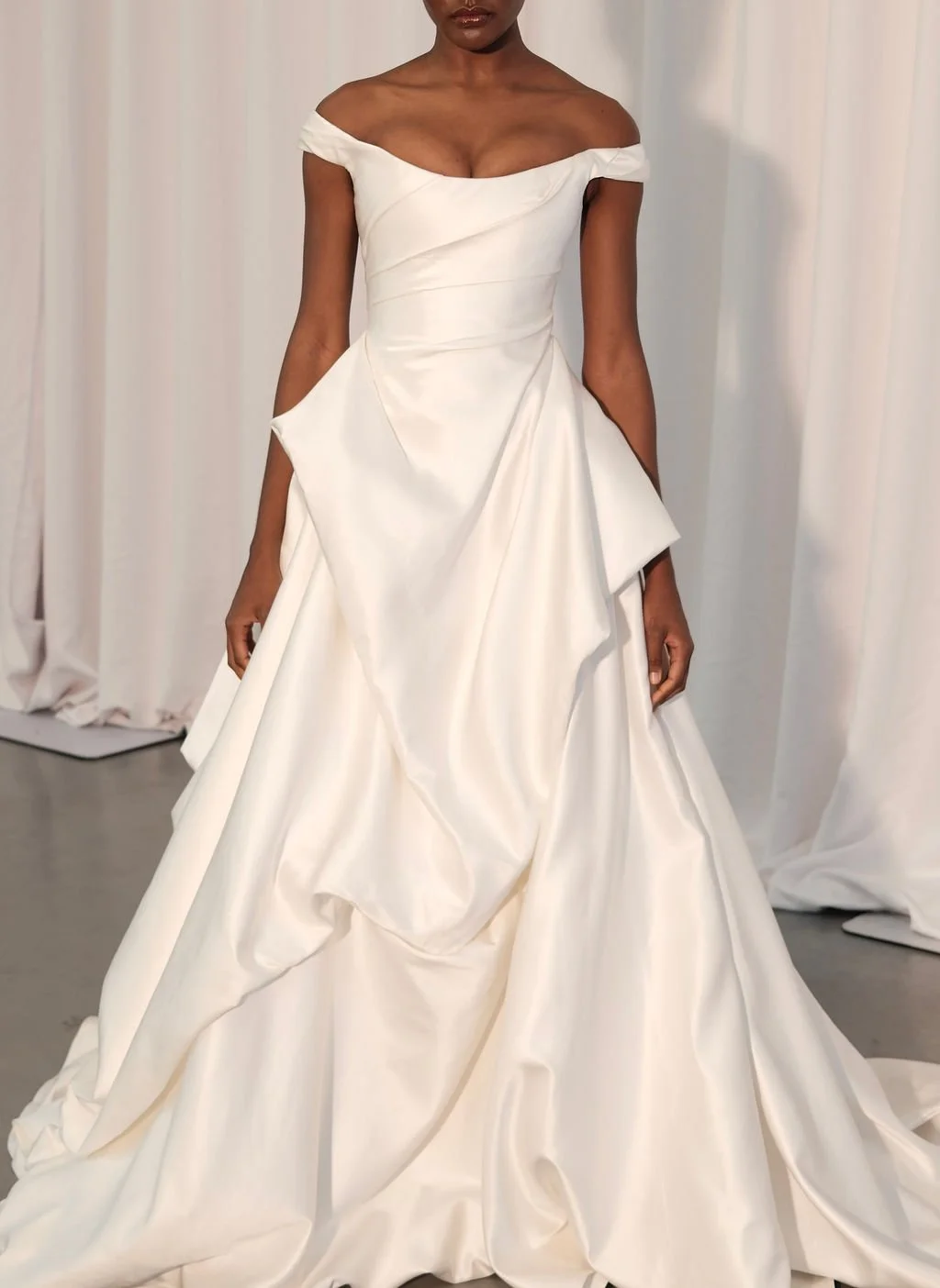 Cool girls wear KYHA Bride Willis. Luxe ivory silk satin is directionally draped across the front bodice and crafted into architectural side folds in a celebration of the female form. A full draped skirt and a sweeping train create a more-is-more sta