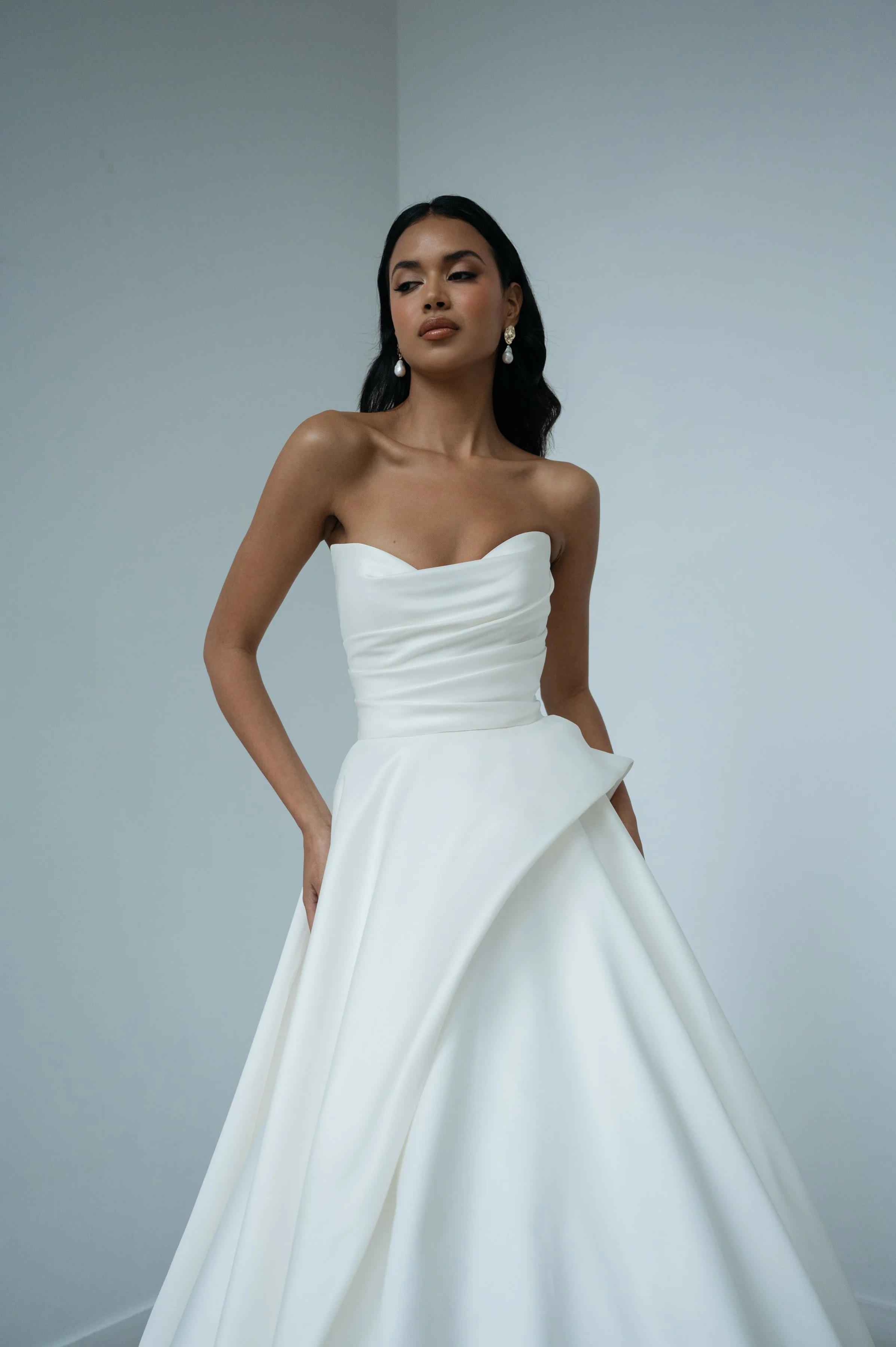 The Jenny Yoo Bridal Gardenia gown  is a refined, minimalist satin design with a clean, structured bodice and effortless drape. It features a flattering neckline and a sleek, flowing skirt that creates a modern yet timeless bridal silhouette.