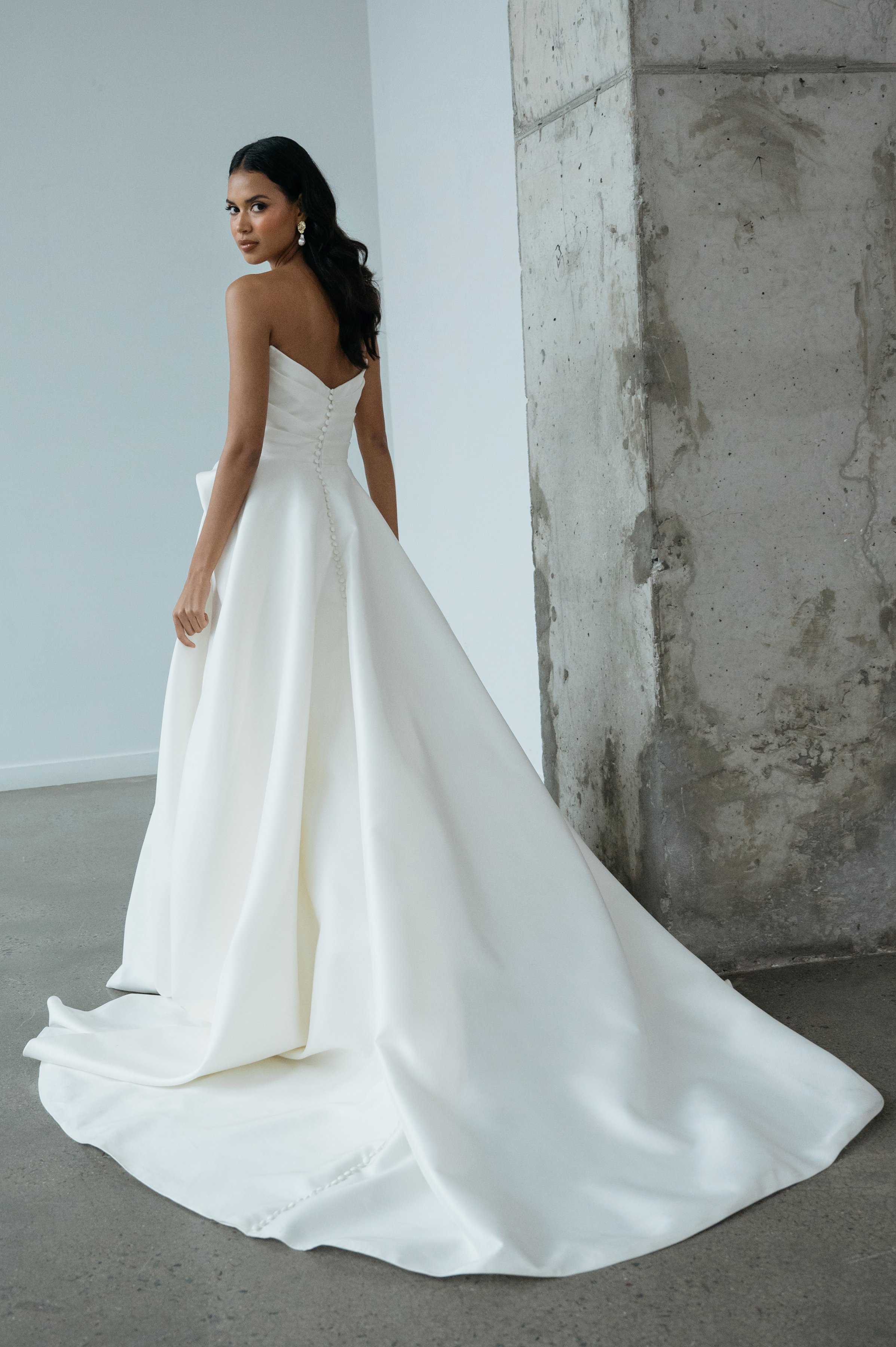 The Jenny Yoo Bridal Gardenia gown  is a refined, minimalist satin design with a clean, structured bodice and effortless drape. It features a flattering neckline and a sleek, flowing skirt that creates a modern yet timeless bridal silhouette.