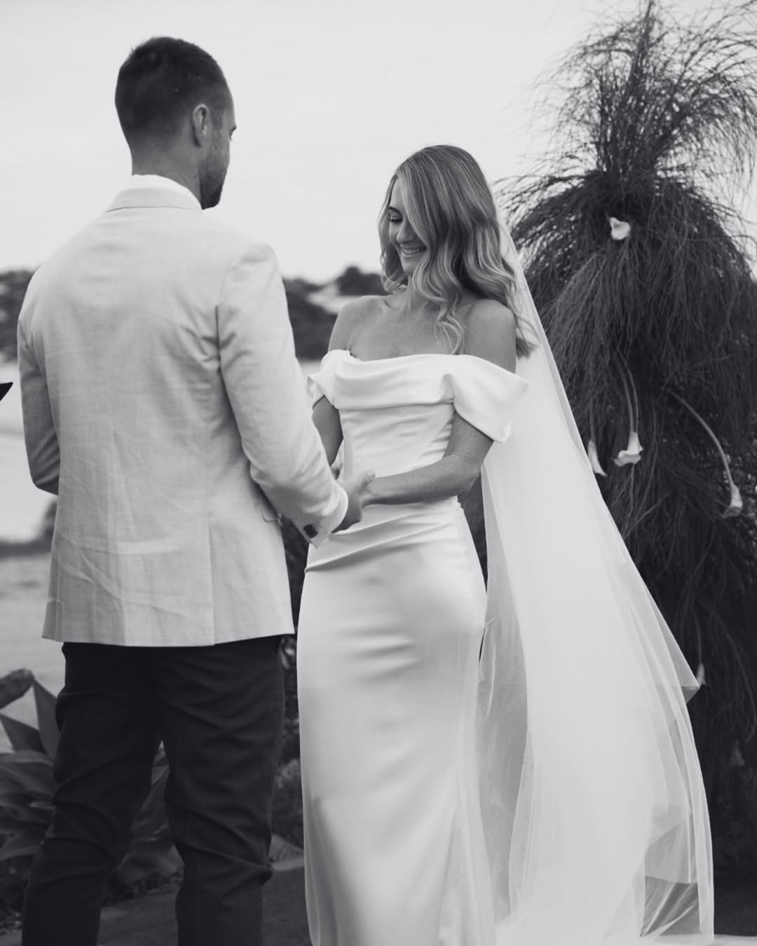 The MWL Brooks is crafted from luxurious satin crepe, featuring an asymmetrical waistline, a structured boned bodice, and a soft front cowl. A sleek column skirt with four pleats creates an elegant, elongated silhouette. Available at Halo and Wren Br