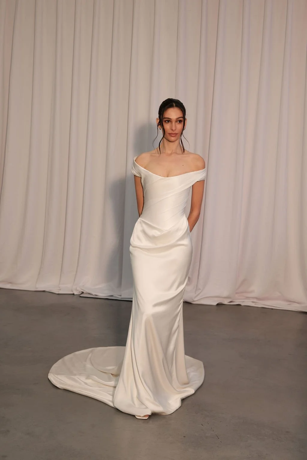 Irreverent glamour takes the spotlight in KYHA Bride Nia. Cut from sleek double satin, Nia features a highly structured bodice with a tight drape and a fit-and-flare skirt cut to accentuate the silhouette. The draping graciously falls into a floor-sw