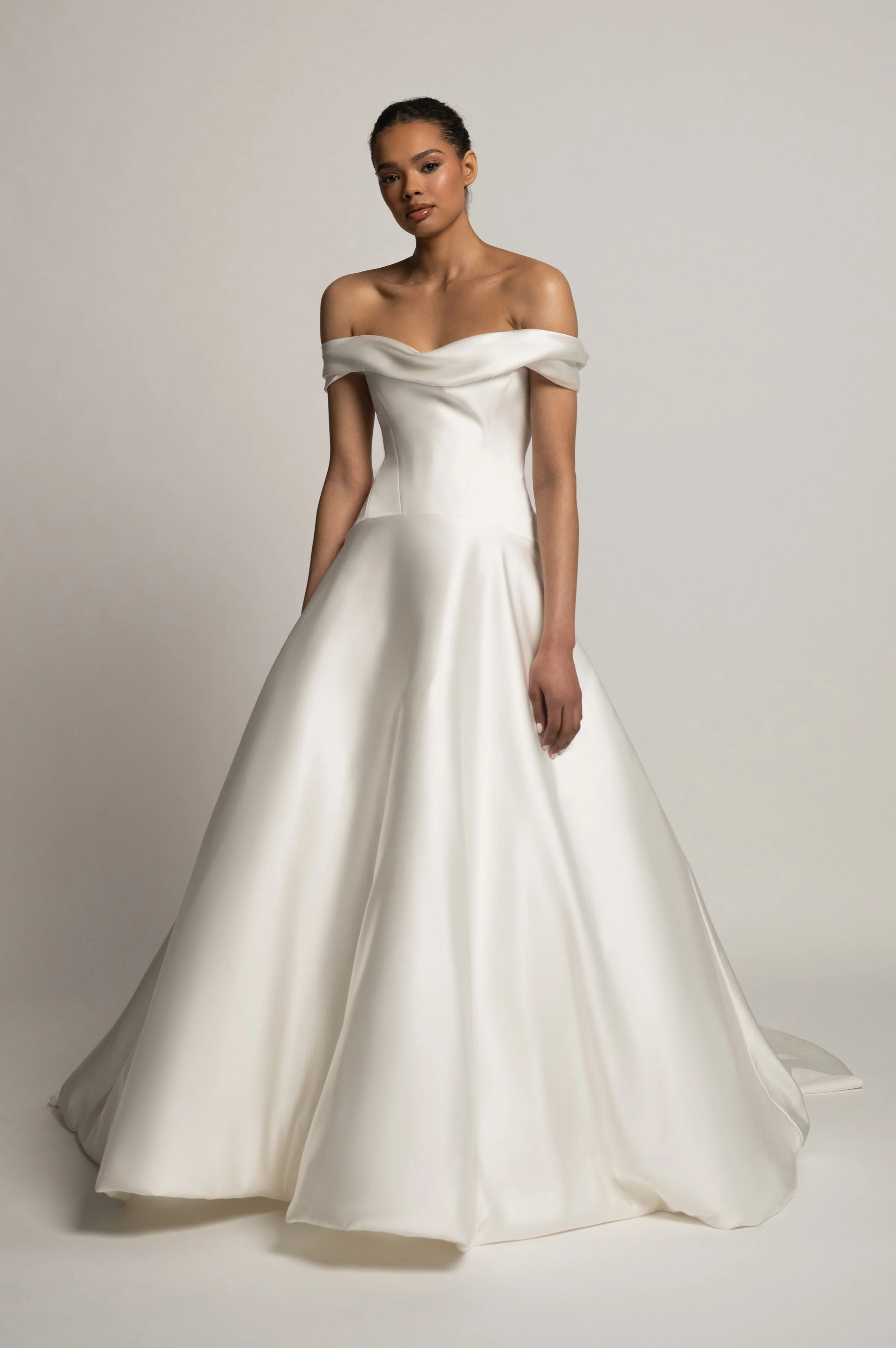 The Jenny Yoo Bridal Greer gown, our second collaboration with renowned bridal stylist, Hope LaVine, is as modern as she is timeless. Featuring a softly draped off the shoulder neckline, angled corset seam details, and a curved drop waist, she is stu