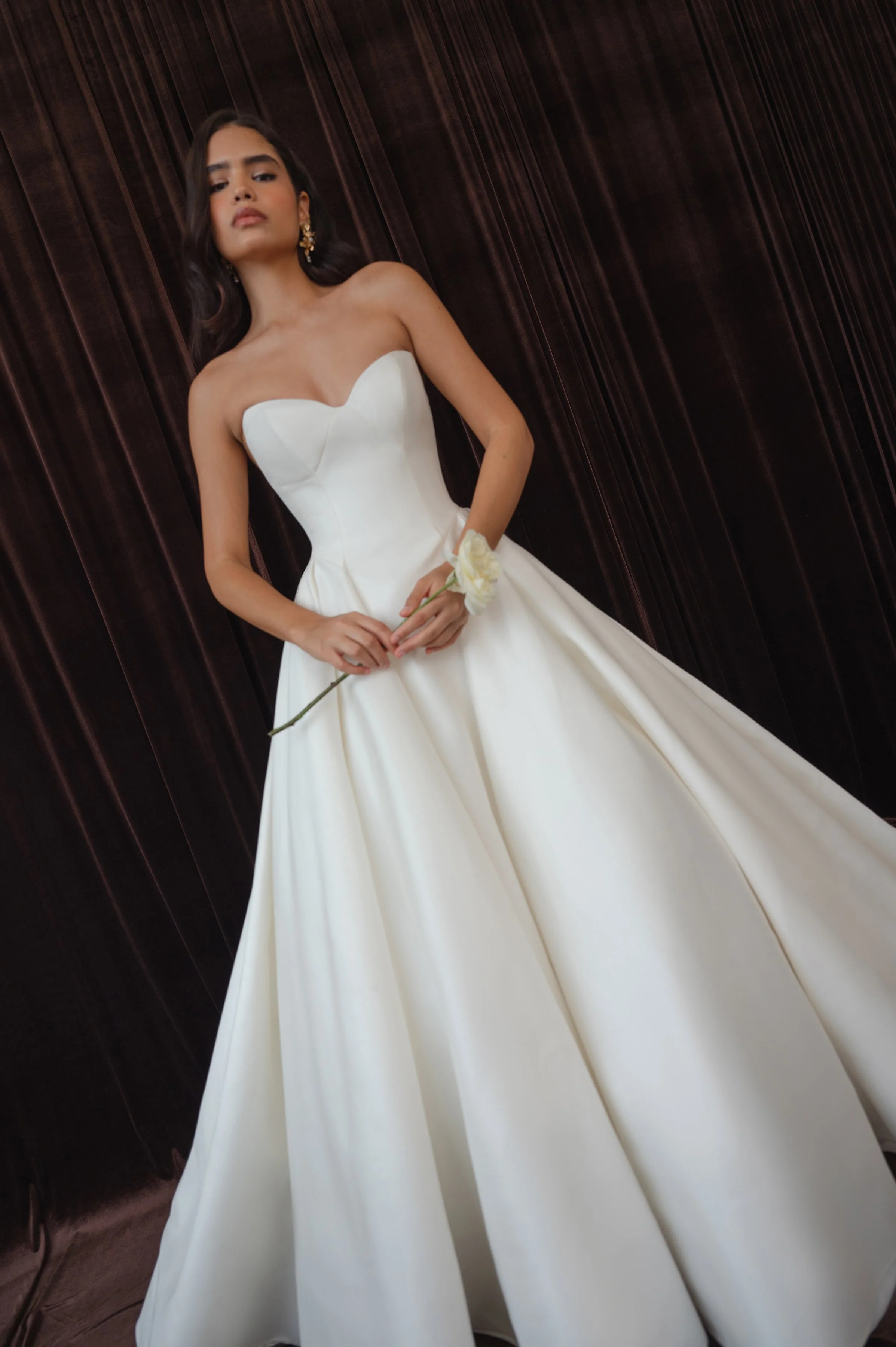 The Jenny Yoo Bridal Colette gown, cut in our light and lustrous Italian taffeta fabric is a clean, yet striking show stopper. Intricate seam details sculpt a bustier bodice and subtle drop waist silhouette. Pleats in the ball skirt create dramatic v