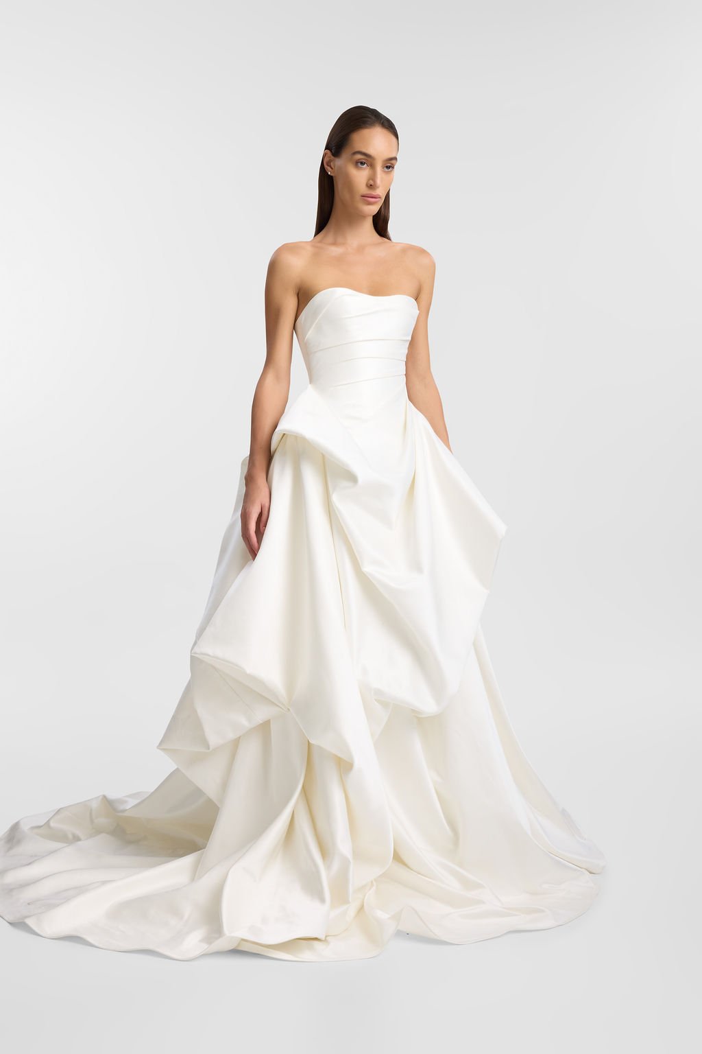 KYHA Bride Preston: an ode to eras past. A fresh take on tradition, Preston brings a modern edge thanks to its structural draping, showstopping train and architectural dropped waist. Crafted from luxe silk satin, Preston’s strapless silhouette, struc