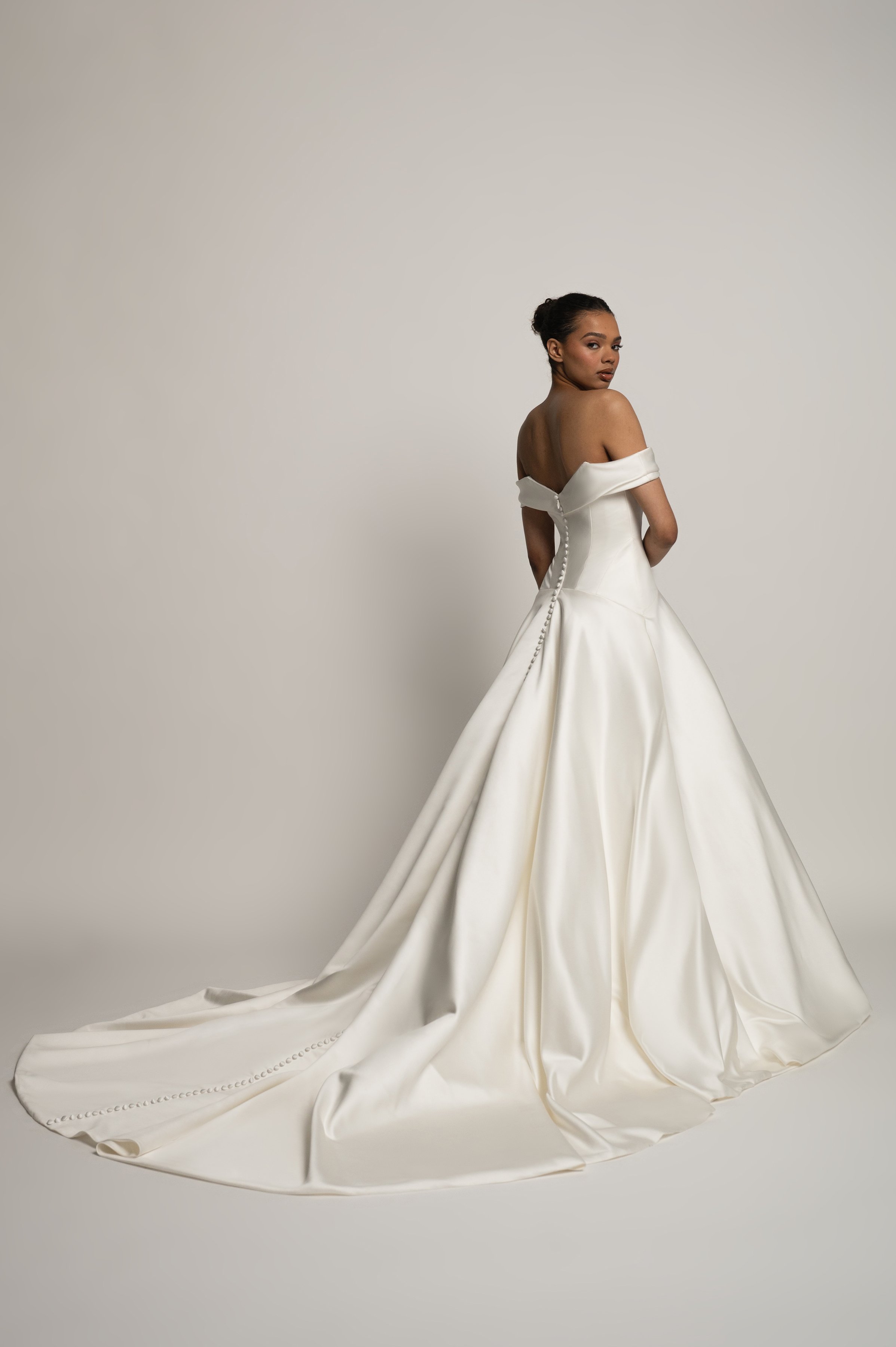 The Jenny Yoo Bridal Greer gown, our second collaboration with renowned bridal stylist, Hope LaVine, is as modern as she is timeless. Featuring a softly draped off the shoulder neckline, angled corset seam details, and a curved drop waist, she is stu