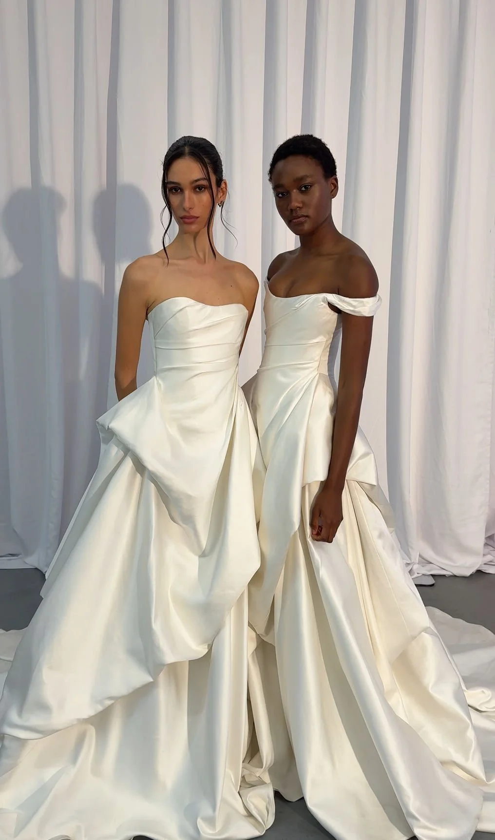 Cool girls wear KYHA Bride Willis. Luxe ivory silk satin is directionally draped across the front bodice and crafted into architectural side folds in a celebration of the female form. A full draped skirt and a sweeping train create a more-is-more sta