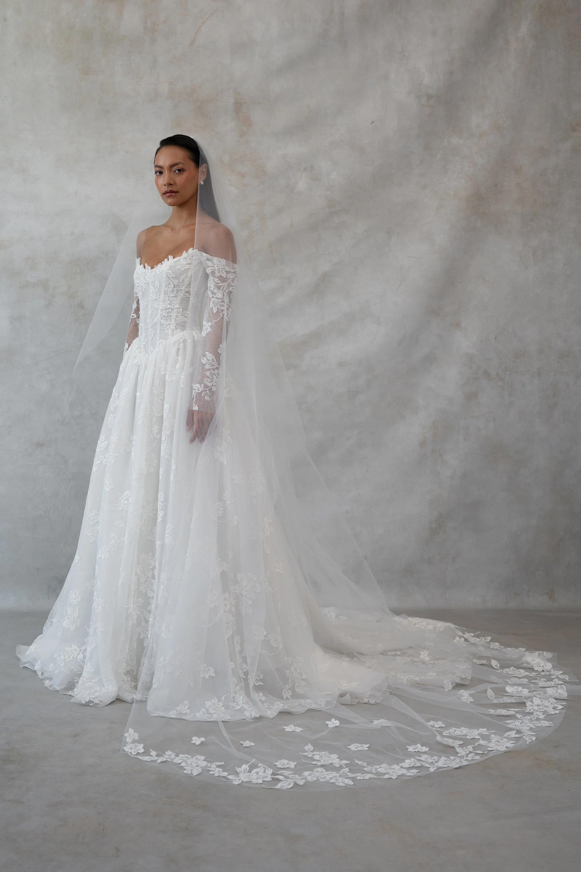 The Jenny Yoo Phoebe gown, cut in our delicately textured Isadora floral embroidery, is as modern as she is romantic. The structured Basque corset bodice leads way to a flowing gathered skirt. Detachable long sleeves lend exciting versatility.