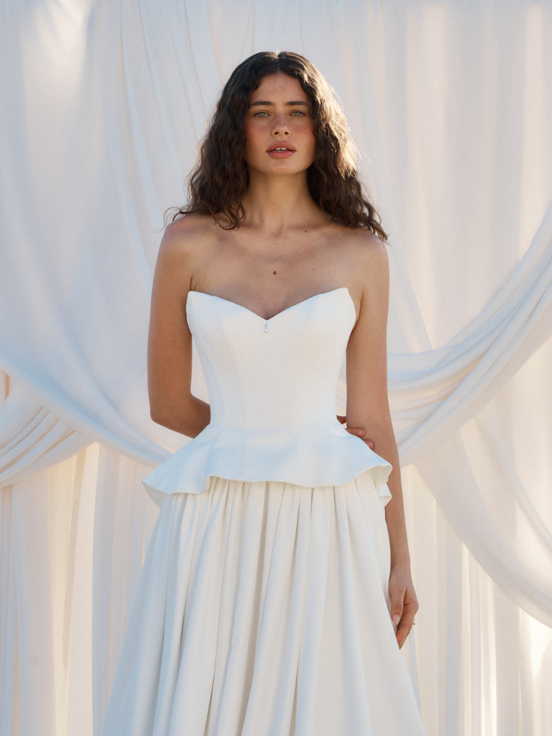 Tanner by MWL, made from our luxurious Avery Satin, the skirt flows beautifully and is finished with a bagged out bubble hem, adding subtle volume and a touch of drama. Inside the bodice, interfacing provides extra support, ensuring a secure and eleg