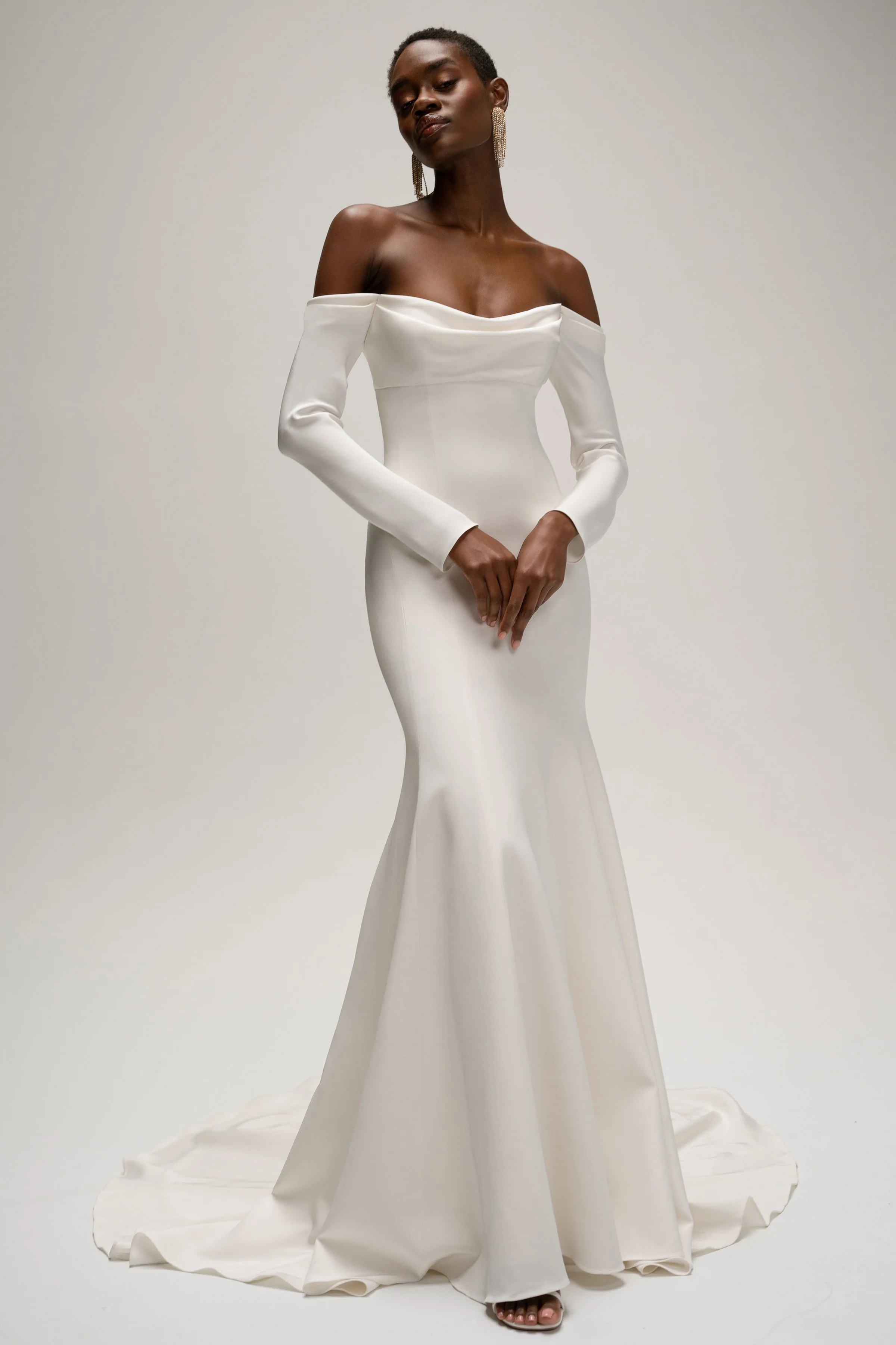 The Jenny Yoo Briar gown is a sophisticated fit-and-flare bridal dress in lustrous silk crepe with a softly draped empire bodice that flatters the décolletage and highlights the shoulders. It features long, slim sleeves and an off-the-shoulder or ele